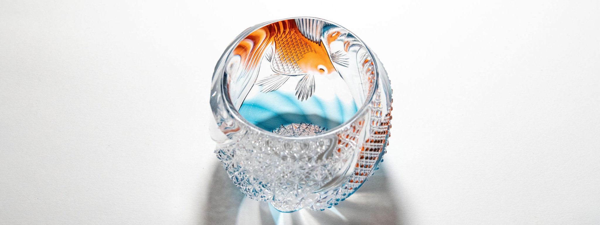 Handcrafted Edo Kiriko sake glass with an amber and orange goldfish design, masterfully carved by Hideyoshi Tadano.