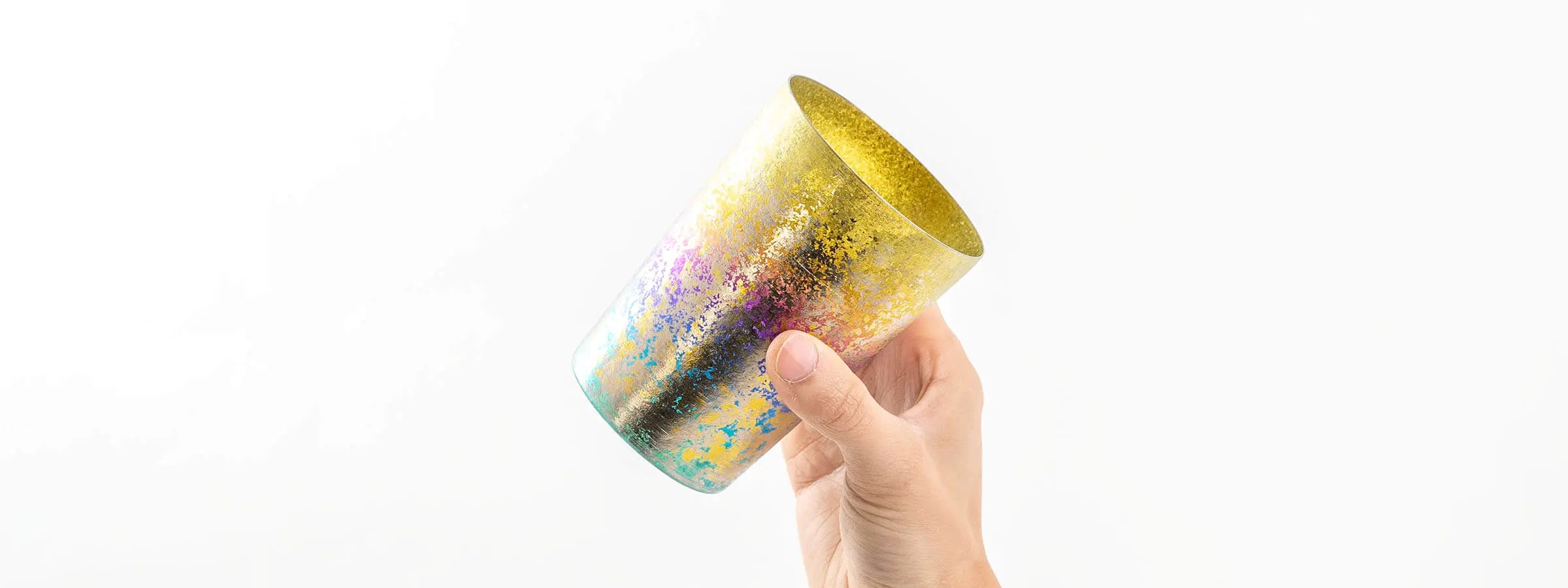 HORIE Taiko Series double-walled titanium tumbler with gold-rainbow splash pattern, Japanese handmade cup held in hand.