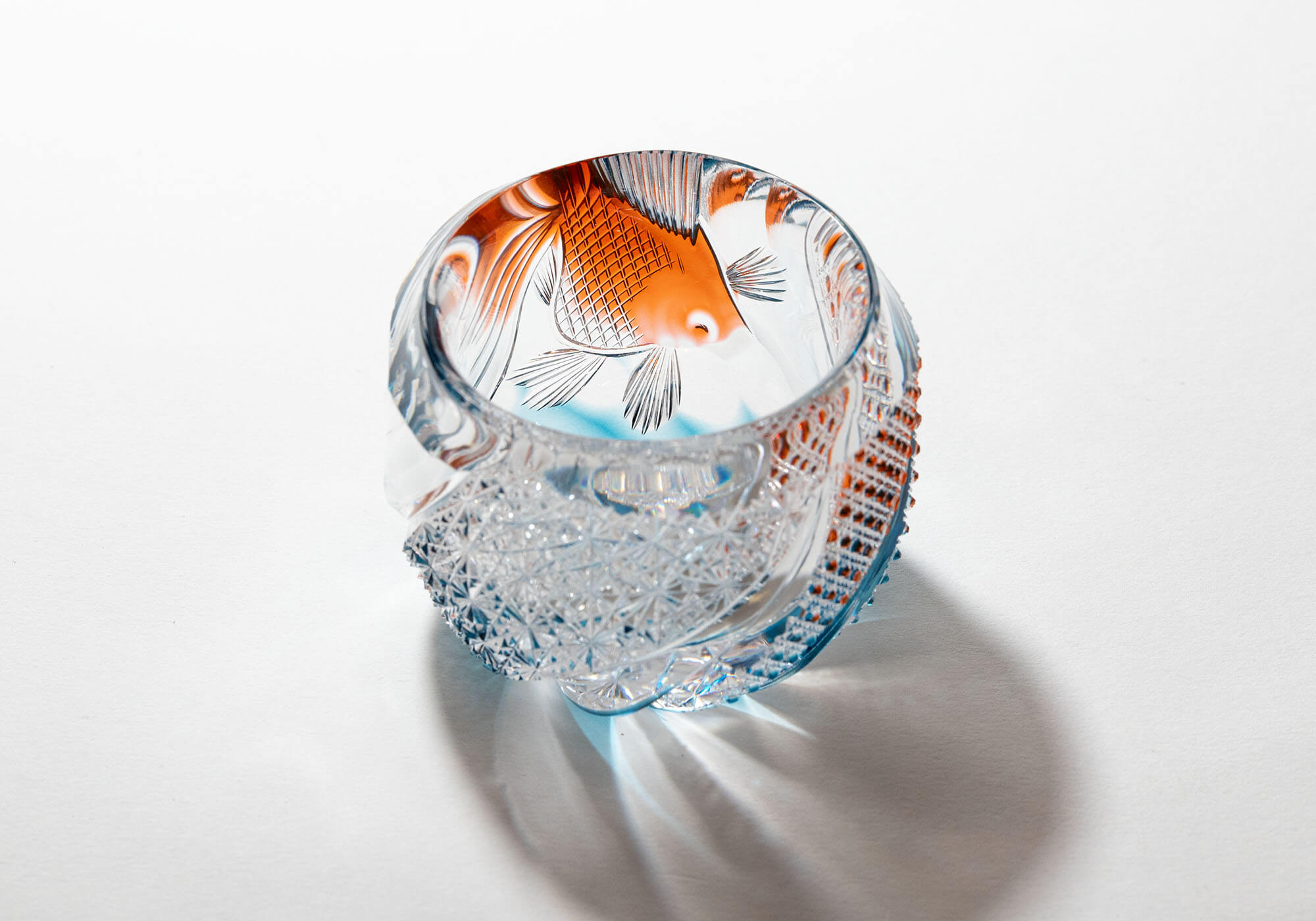 Top-down view of a crystal sake cup showing a carved amber goldfish inside.