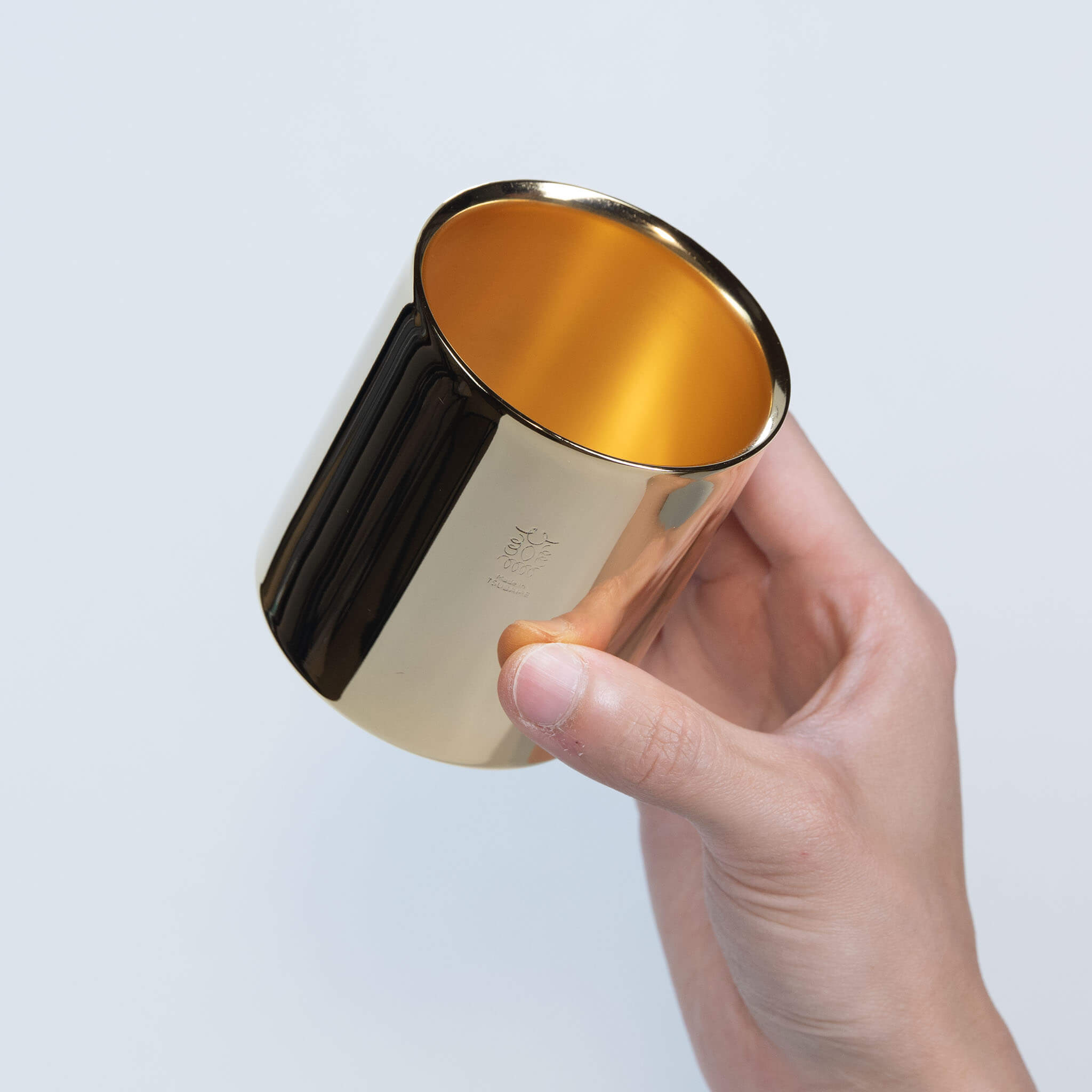 Top view of a person holding the stainless steel tumbler, highlighting the brilliant 24K gold plated interior for beverages.