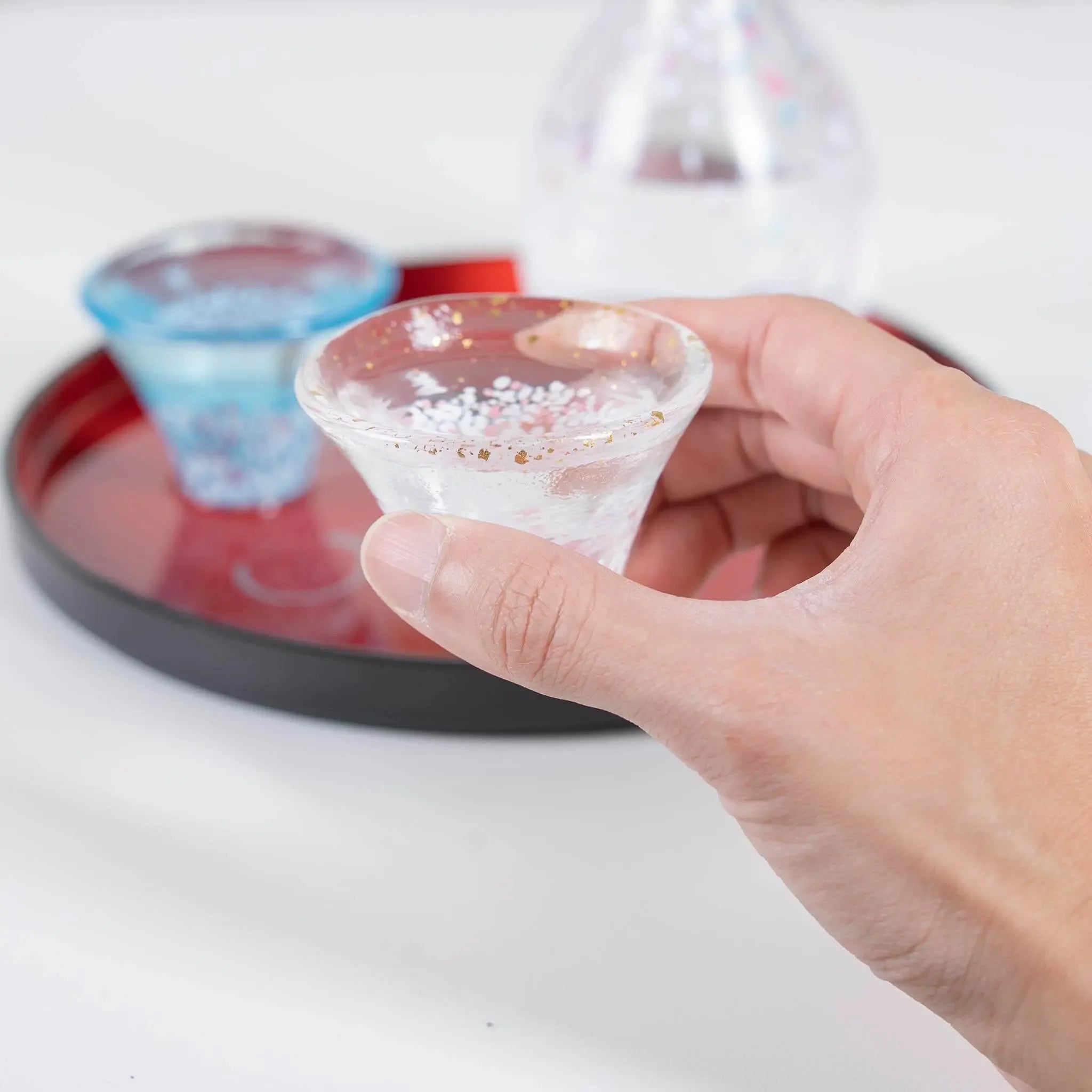 Handheld Japanese sake cup with sakura and Mount Fuji design, showcasing size and drinking experience