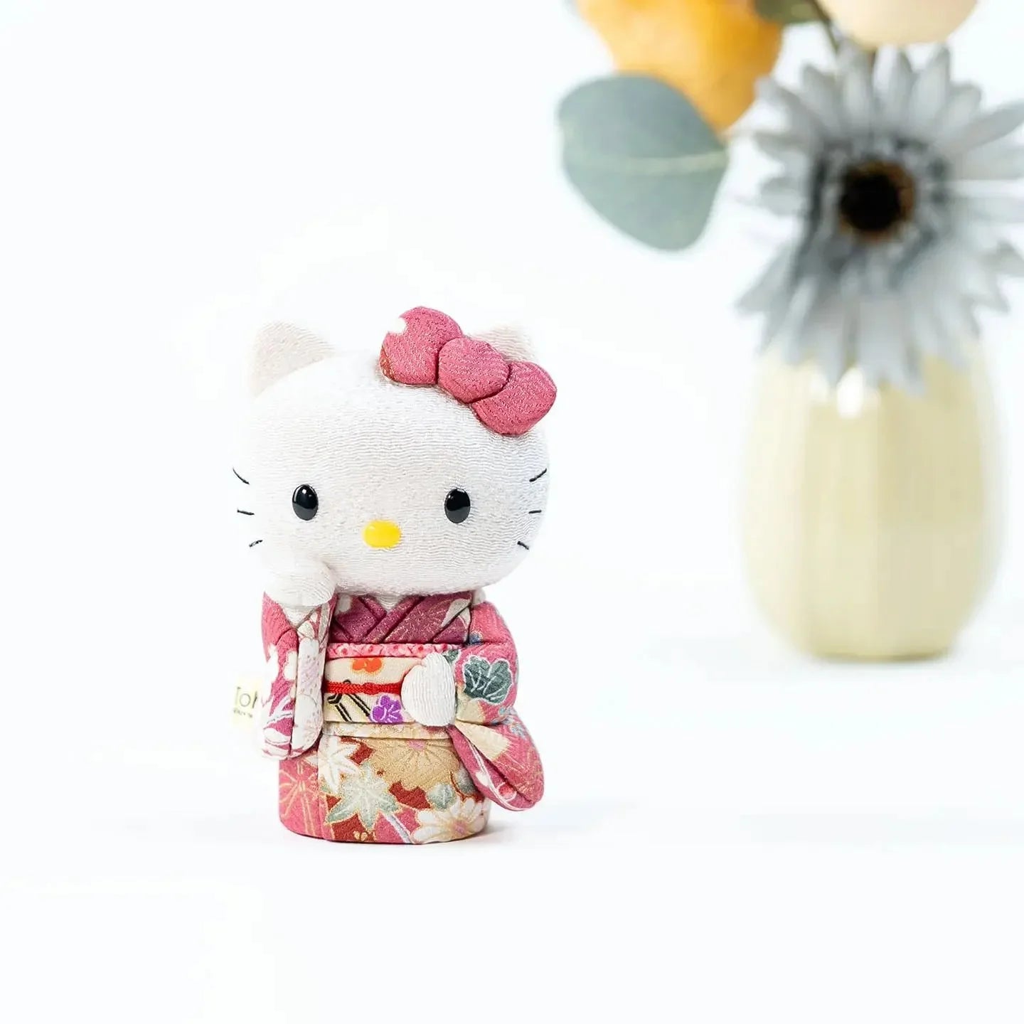 Front view of the Hello Kitty lucky cat doll, showing the intricate details of the pink kimono.