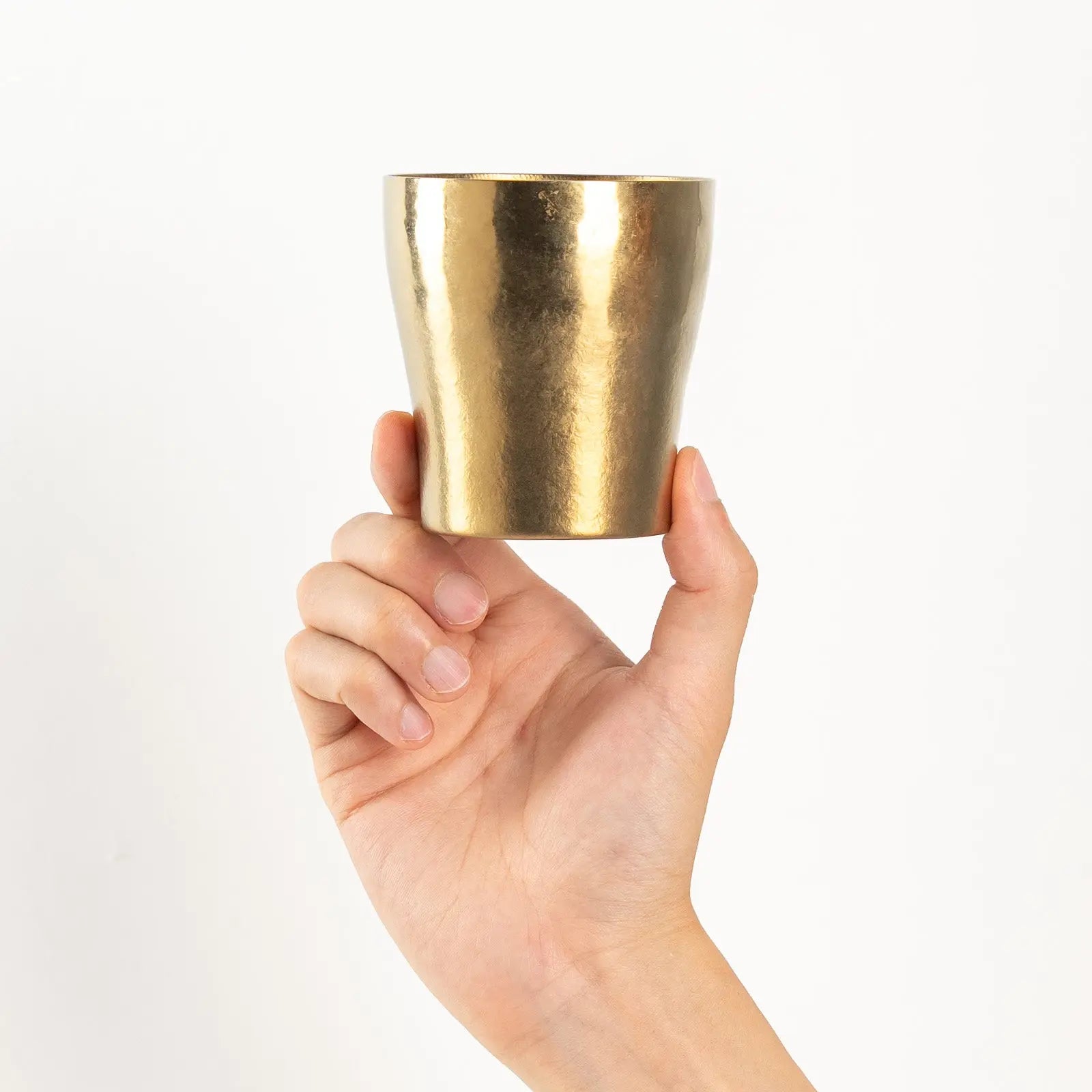 Hand holding bronze gold HORIE tumbler front view