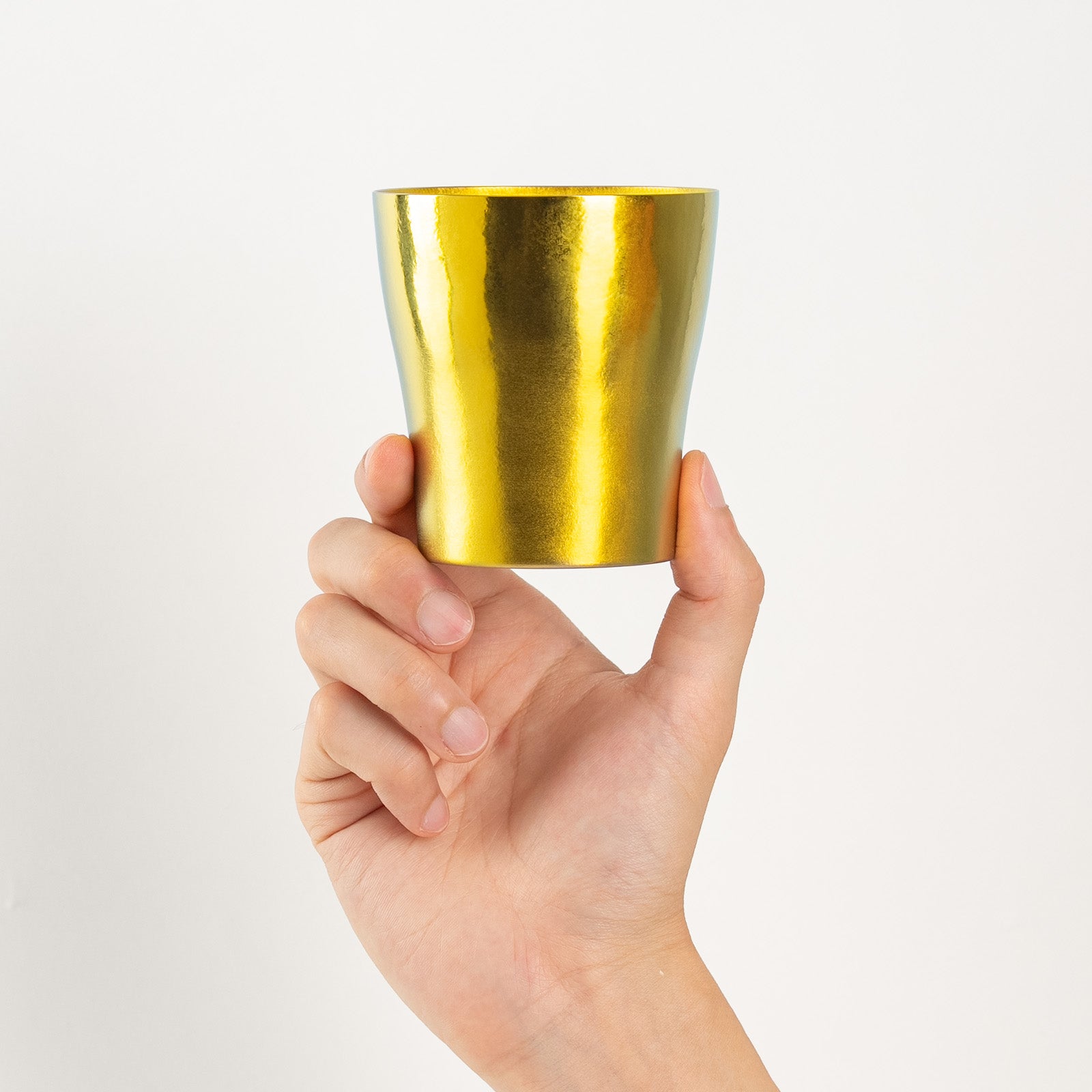 Bright gold titanium tumbler held upright in hand