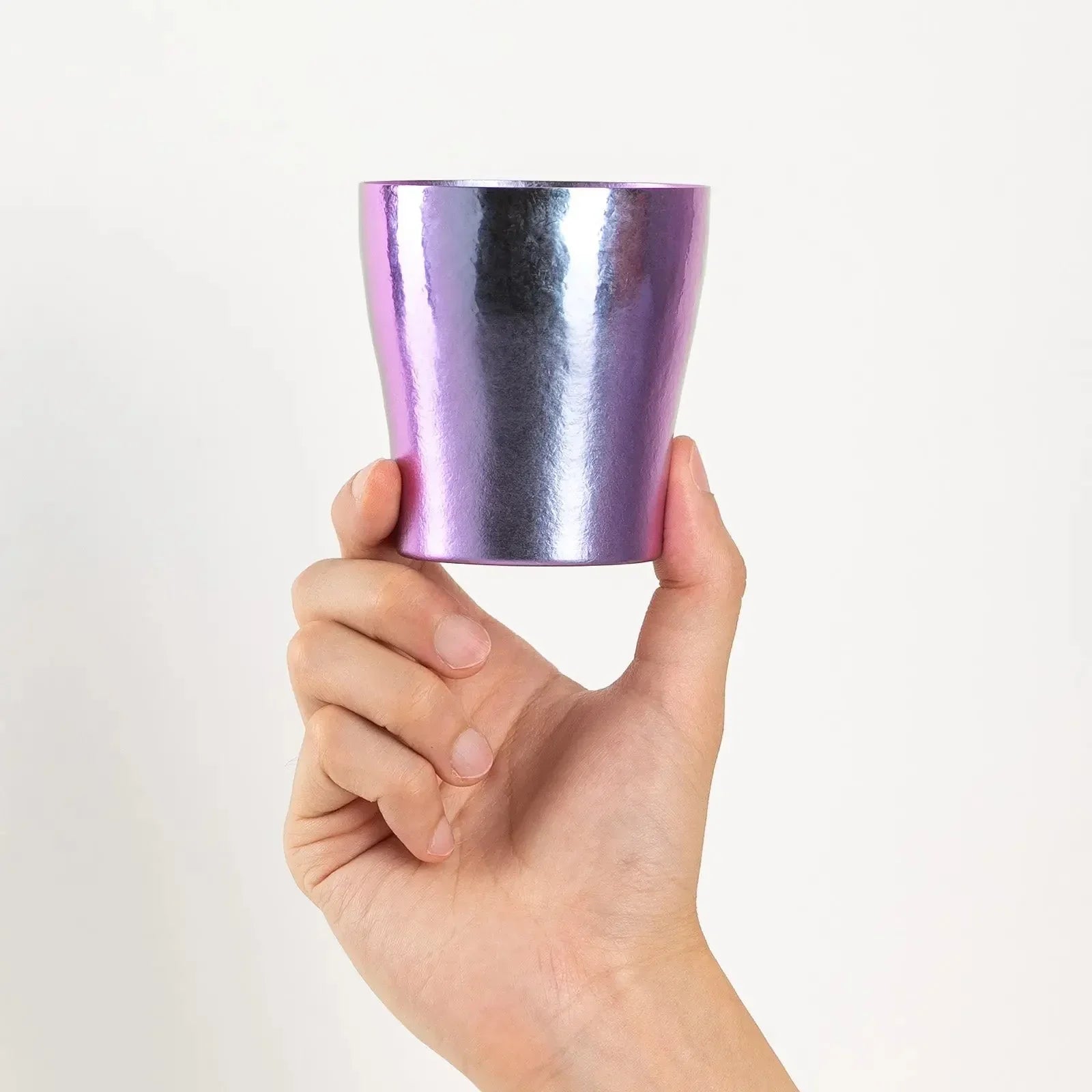 Hand holding rainbow titanium tumbler front view
