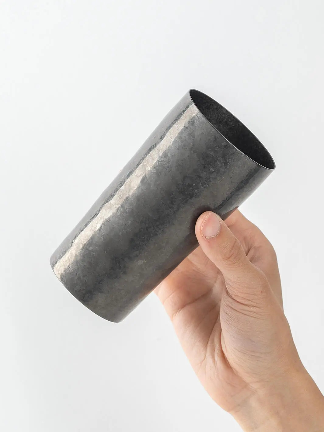 Side view of black HORIE titanium tumbler held in hand