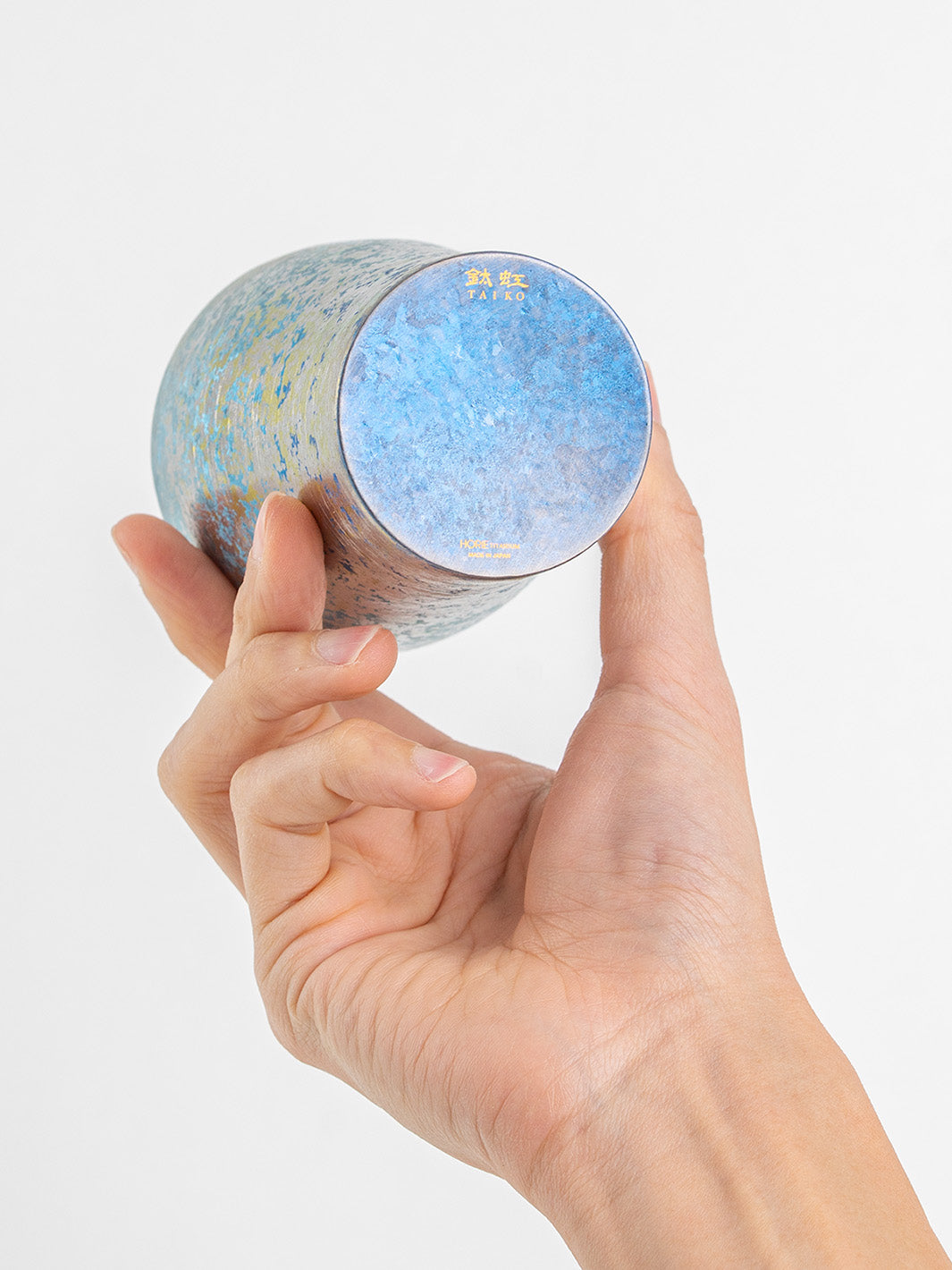 Bottom of blue titanium tumbler displayed in hand