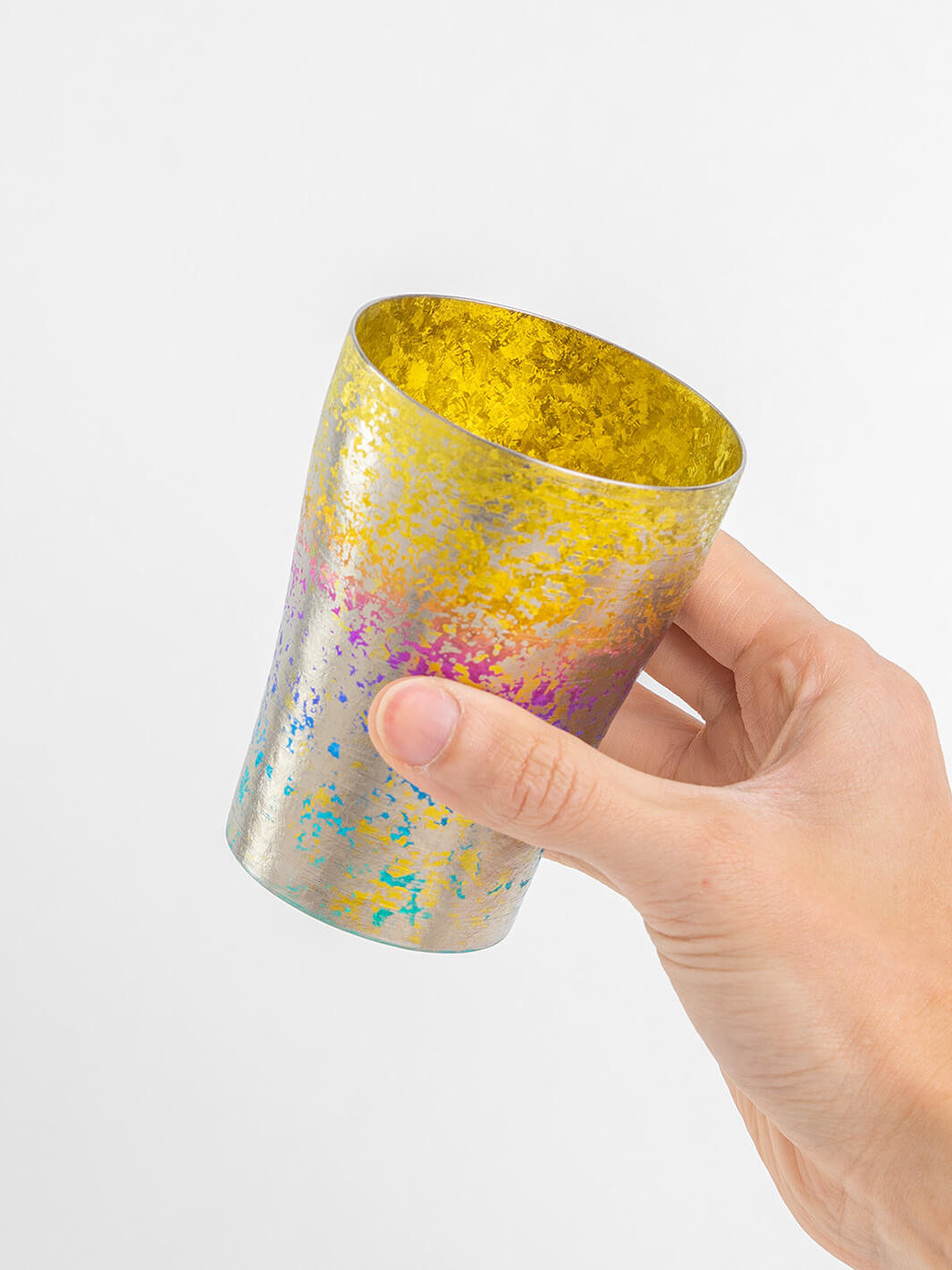 Hand holding rainbow titanium tumbler, side view