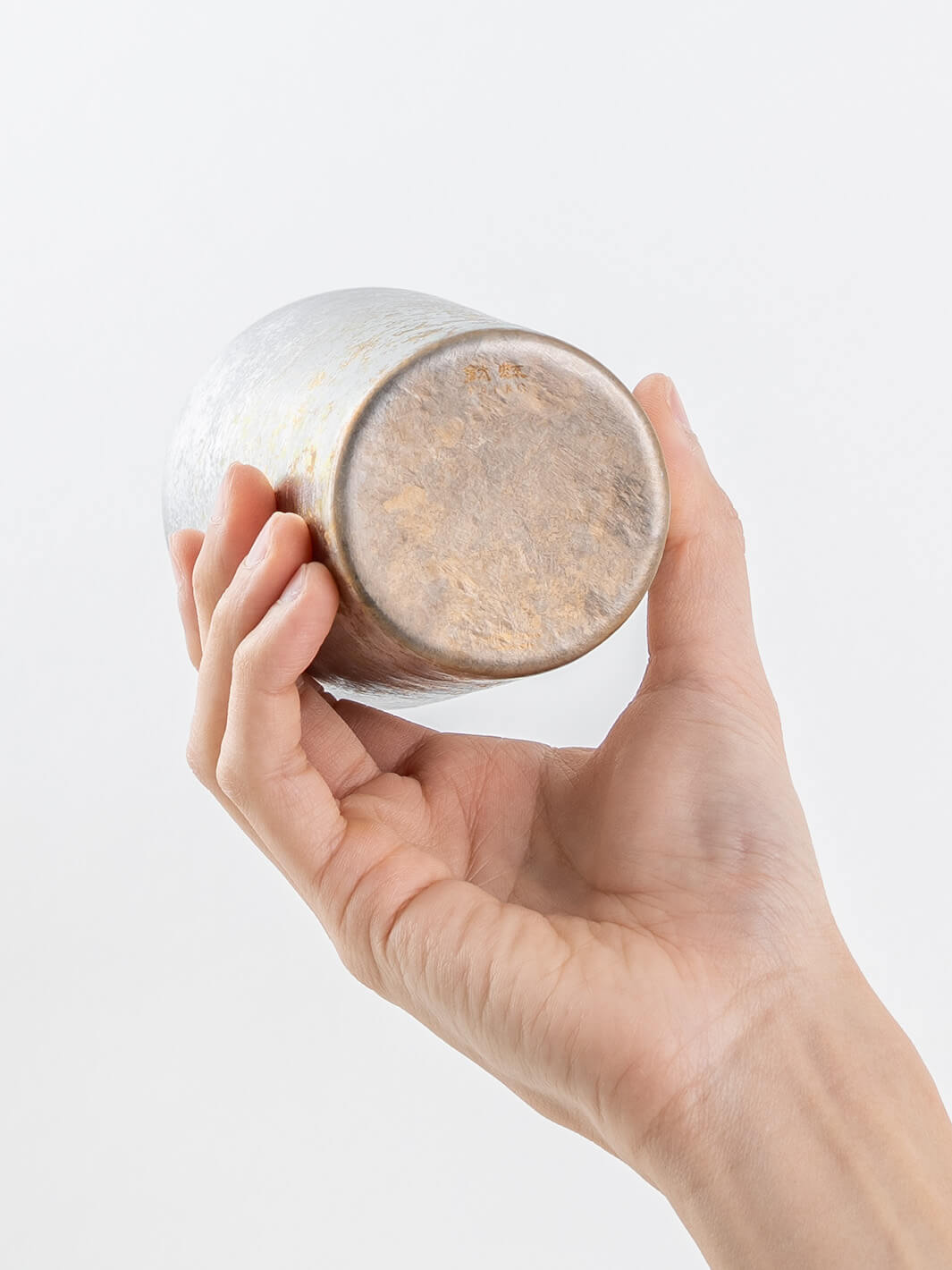 Bottom of silver titanium tumbler shown in hand