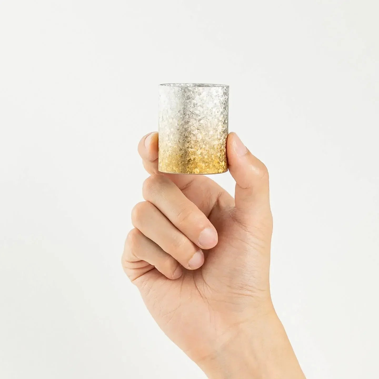 A hand holding the HORIE Titanium Sake Cup to demonstrate its size and scale.