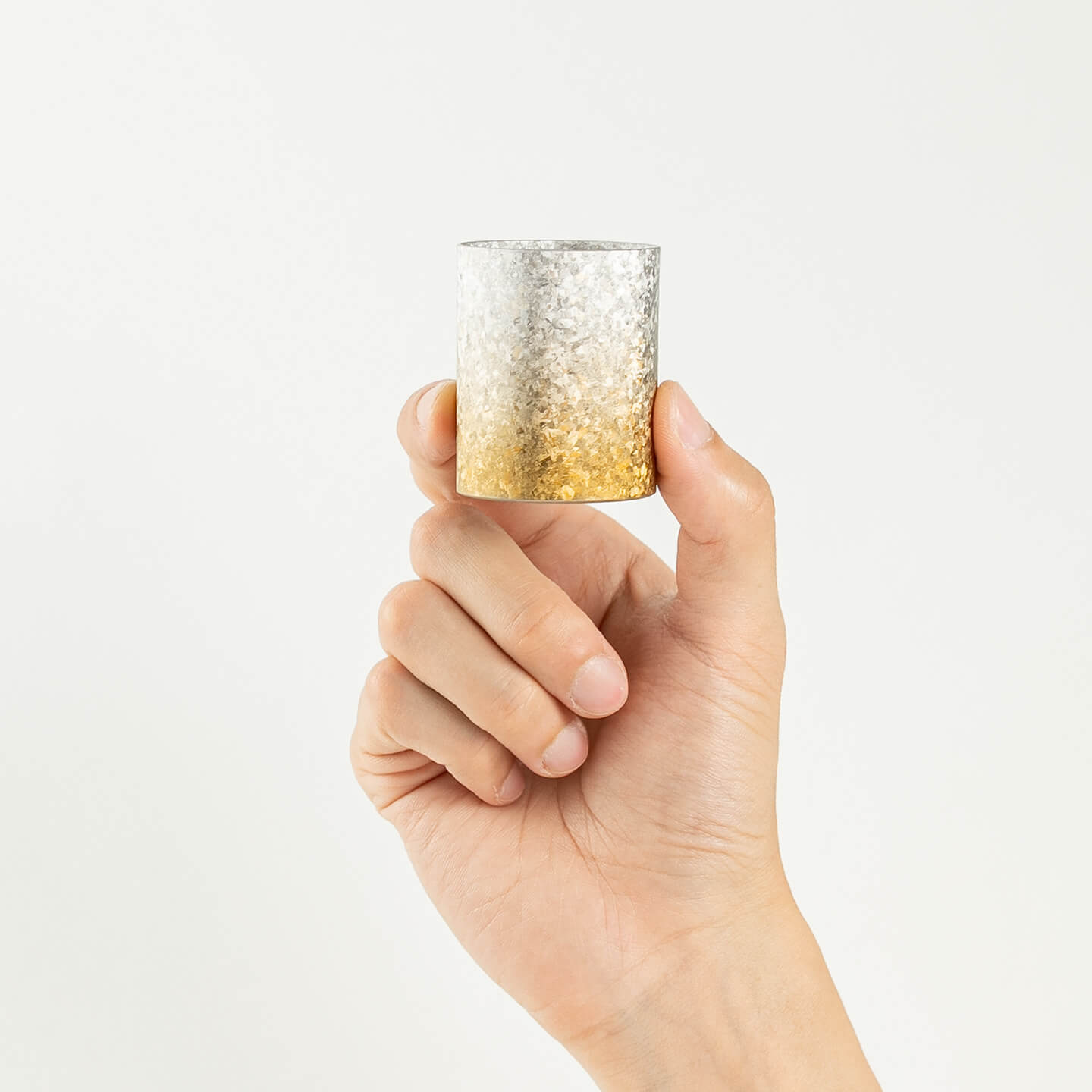A hand holding the HORIE Titanium Sake Cup to demonstrate its size and scale.