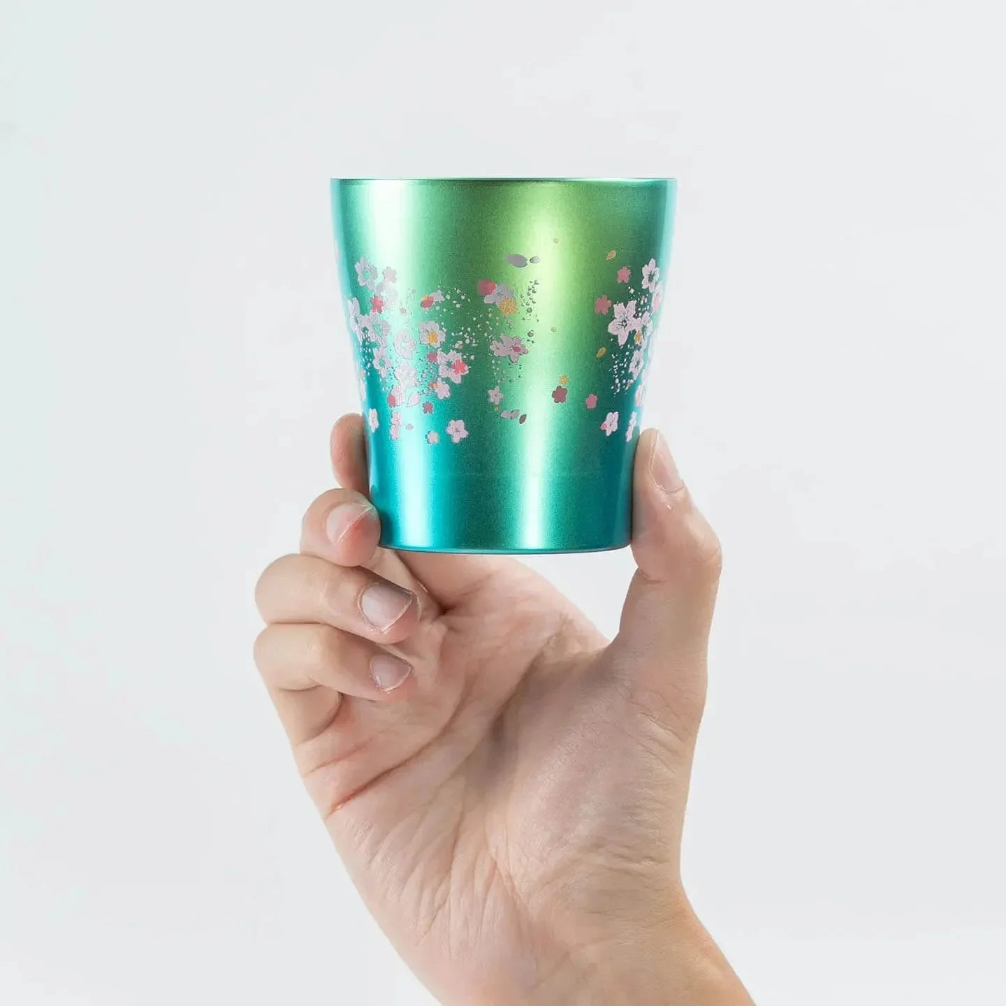 A hand holding the green HORIE Sakura Saku tumbler (250ml) to show its scale.