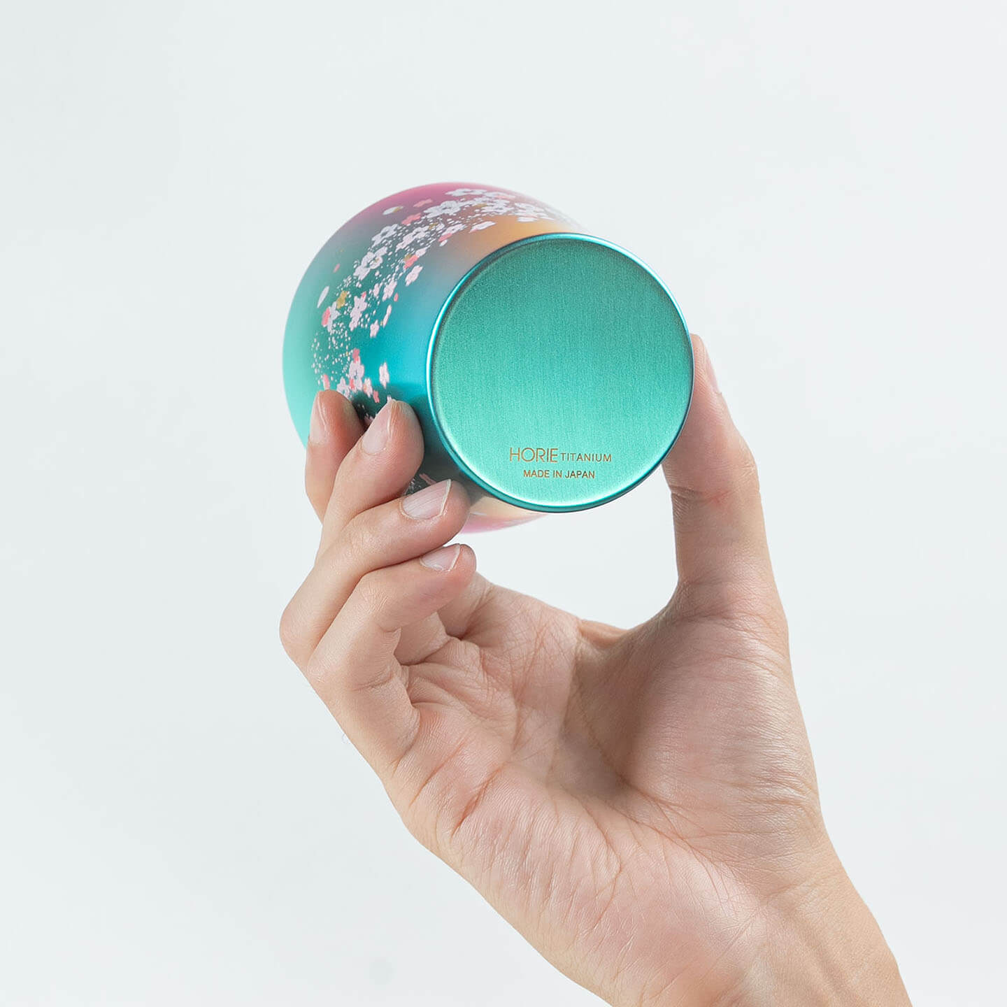 A hand holding the green HORIE tumbler to show the bottom and base detail.