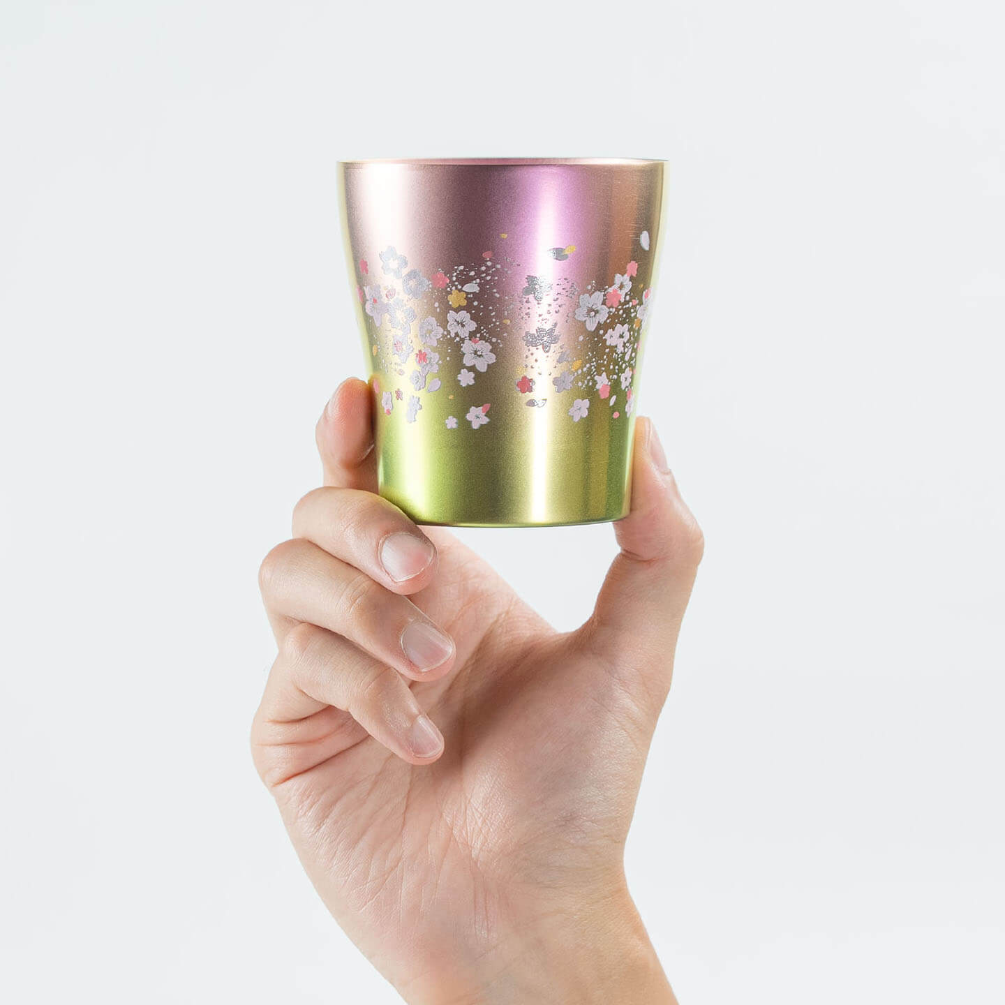 A hand holding the front of the pink HORIE Sakura Saku tumbler to show the 'Sakura Saku' pattern.