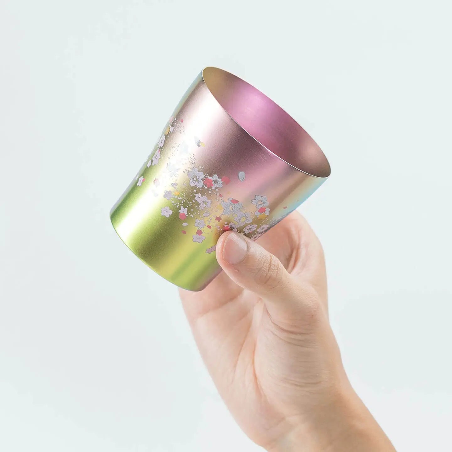 A hand holding the side of the pink HORIE Sakura Saku tumbler.