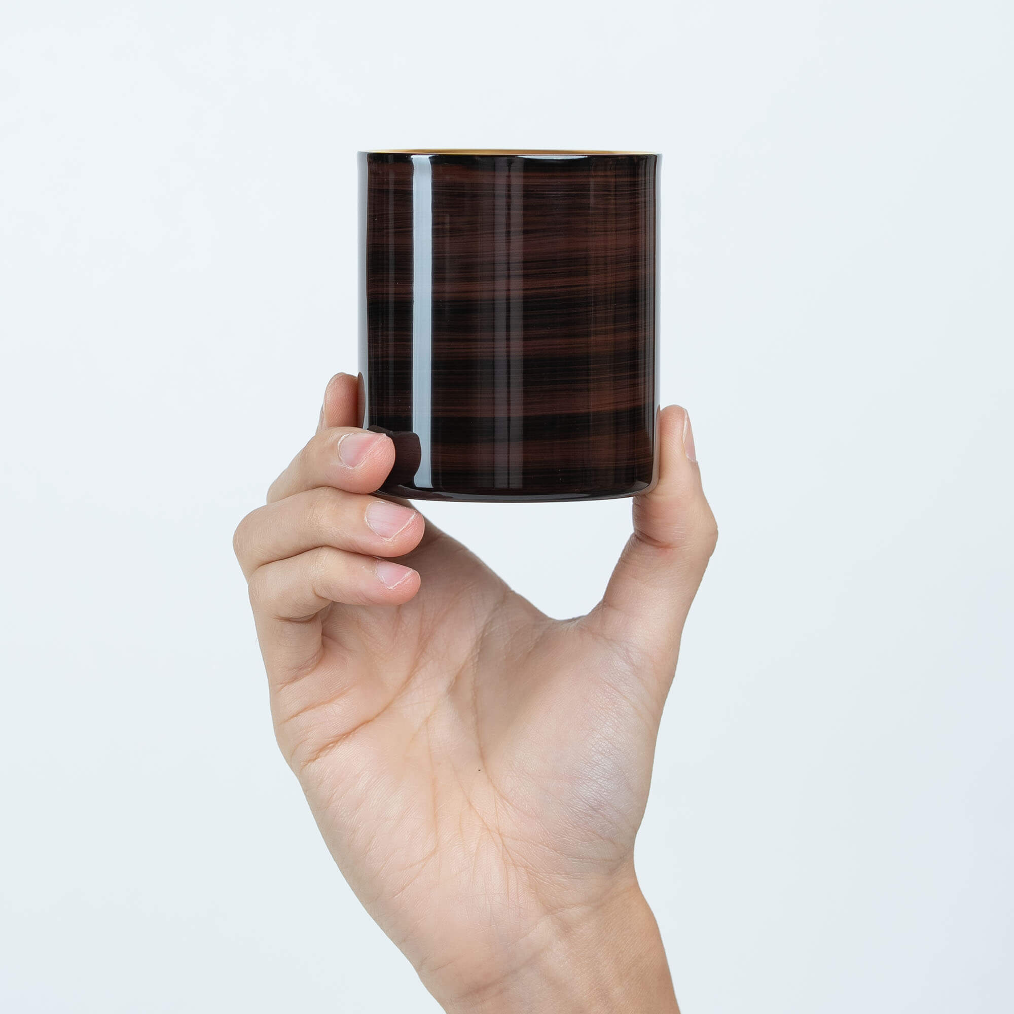 Hand holding a brown Japanese lacquered 250ml stainless steel sake cup upright