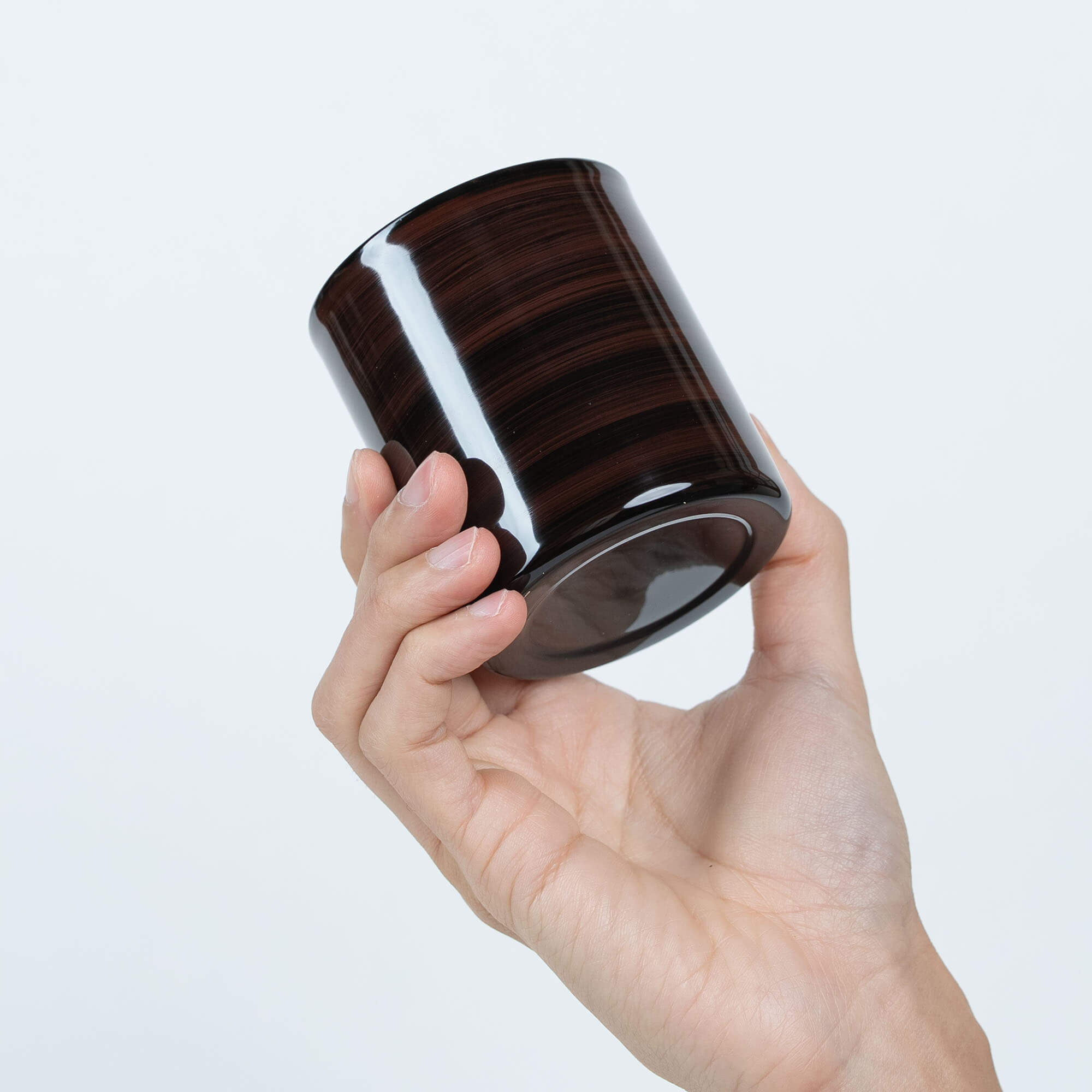 Hand holding a brown Japanese lacquered 250ml stainless steel sake cup at a side angle