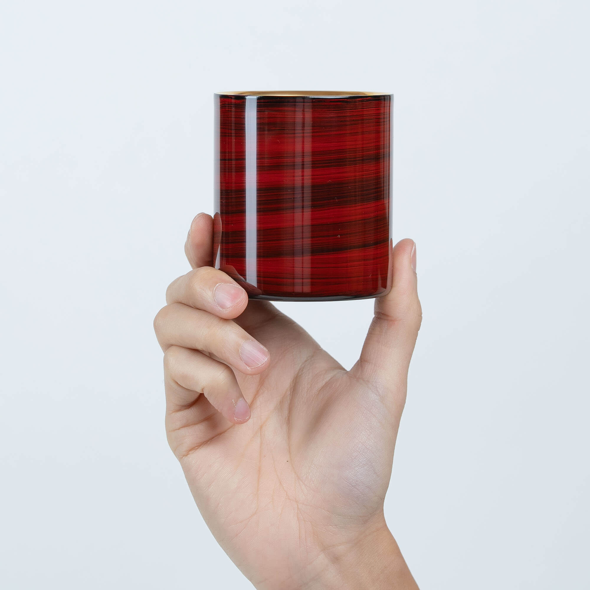 Hand holding a red Japanese lacquered 250ml sake cup upright