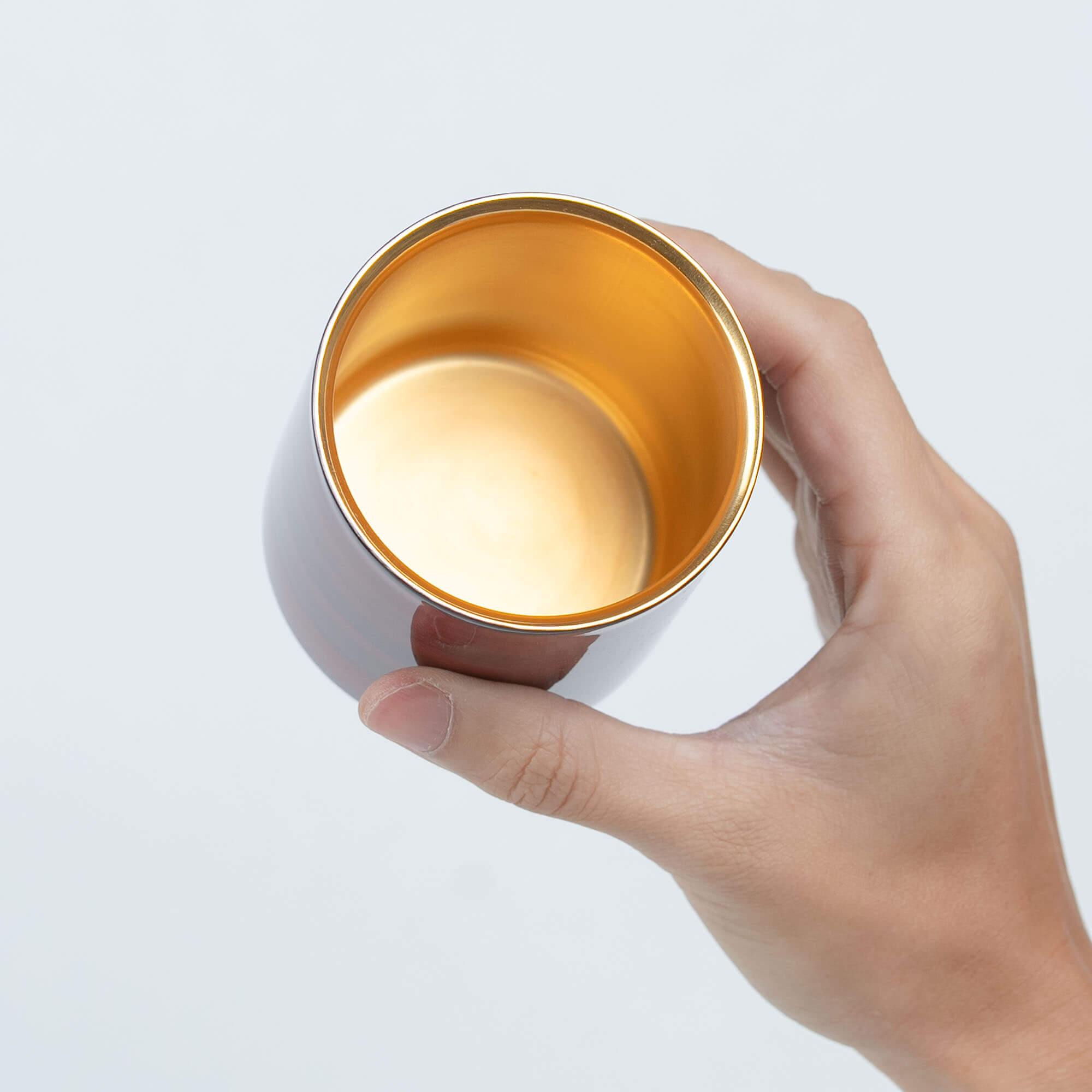 Handheld red lacquered sake cup showing its gold-plated interior