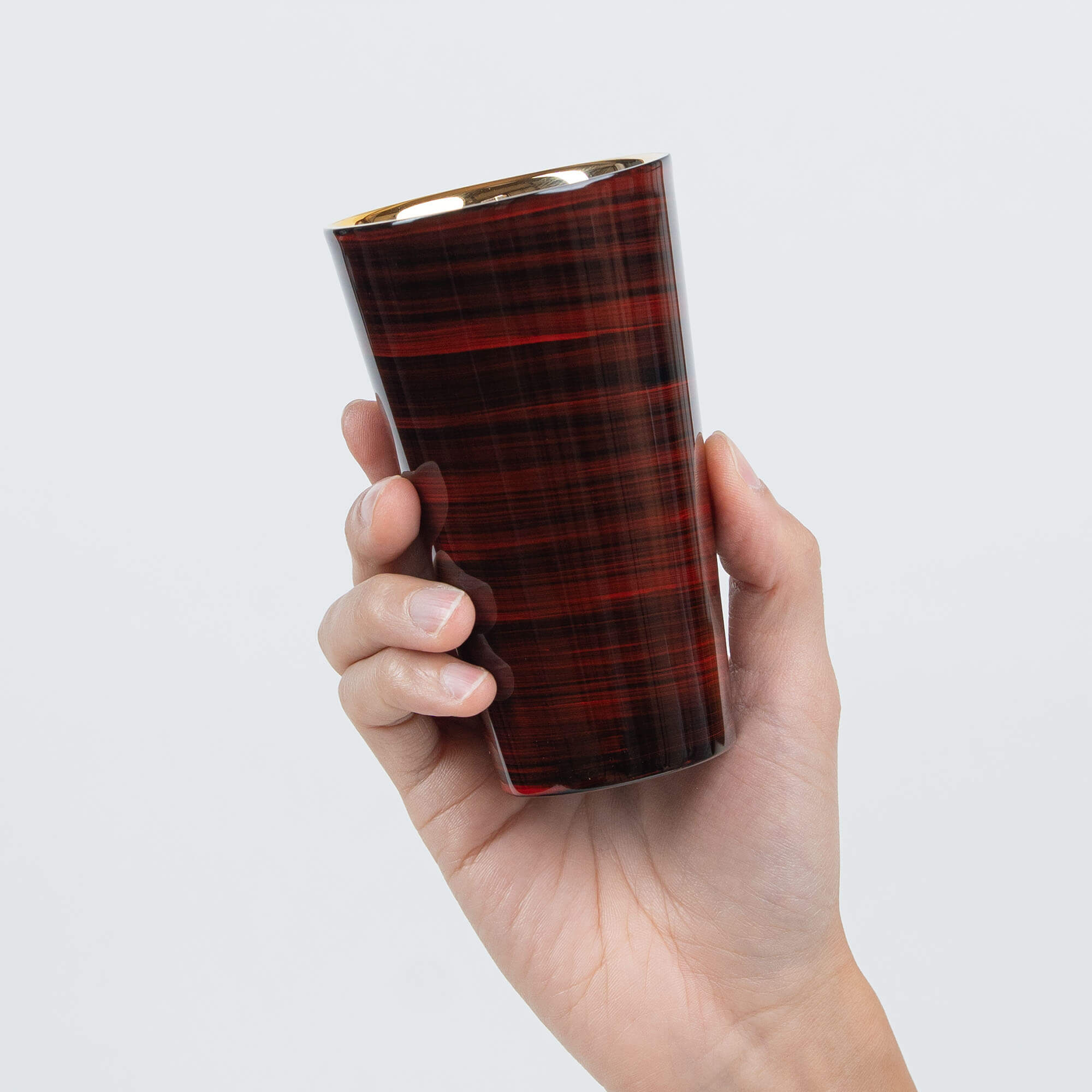 Angled view of a red lacquered stainless steel tumbler with a gold-plated interior
