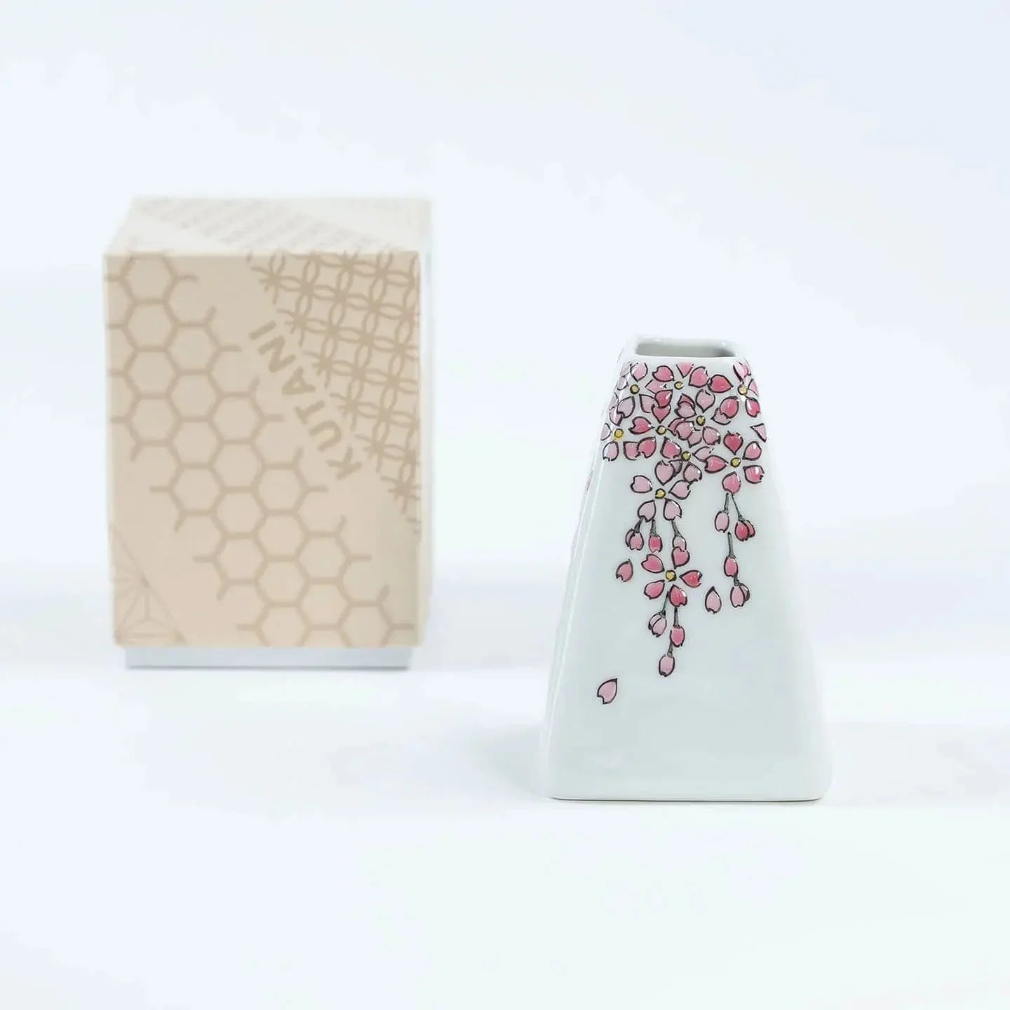 A white Kutani-yaki ceramic vase in the shape of Mt. Fuji with a pink cherry blossom pattern.