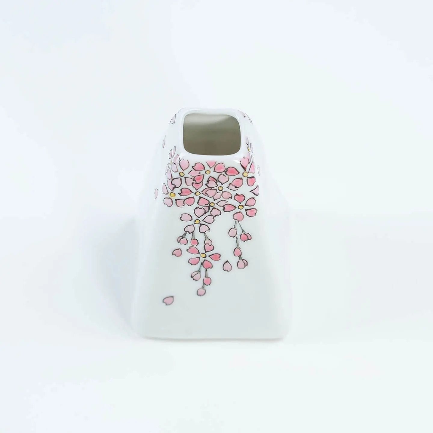 A white Kutani-yaki ceramic vase in the shape of Mt. Fuji with a pink cherry blossom pattern.