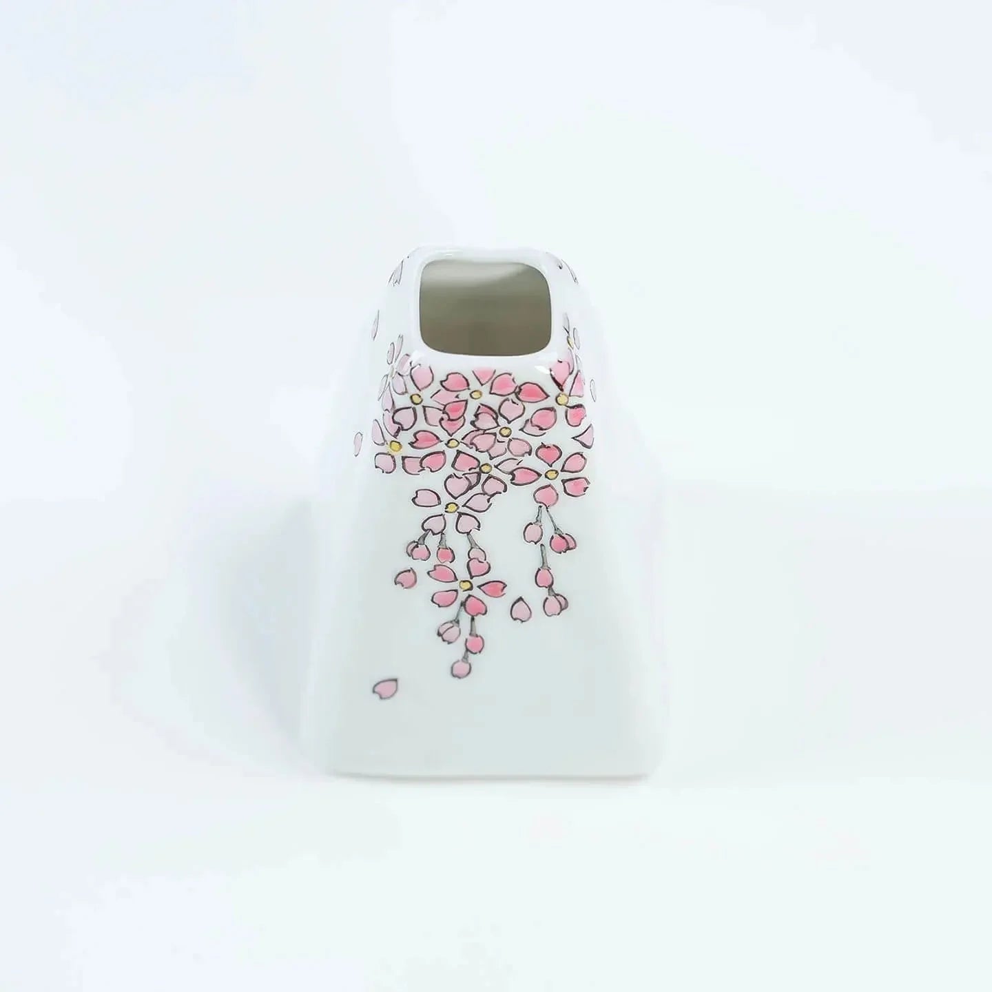 A white Kutani-yaki ceramic vase in the shape of Mt. Fuji with a pink cherry blossom pattern.