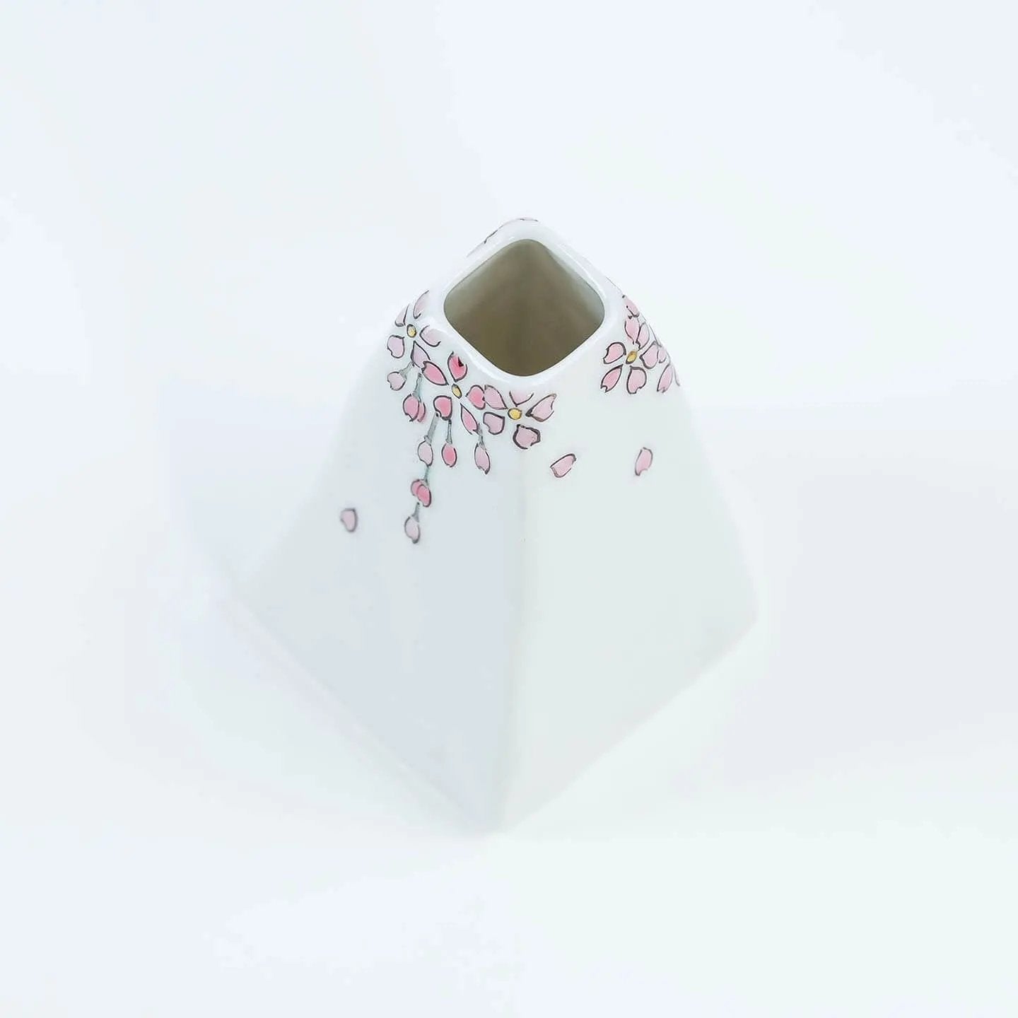 A white Kutani-yaki ceramic vase in the shape of Mt. Fuji with a pink cherry blossom pattern.
