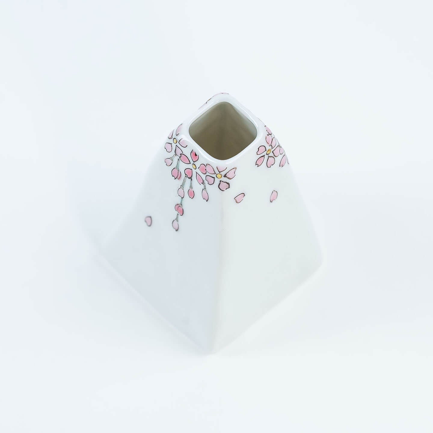 A white Kutani-yaki ceramic vase in the shape of Mt. Fuji with a pink cherry blossom pattern.