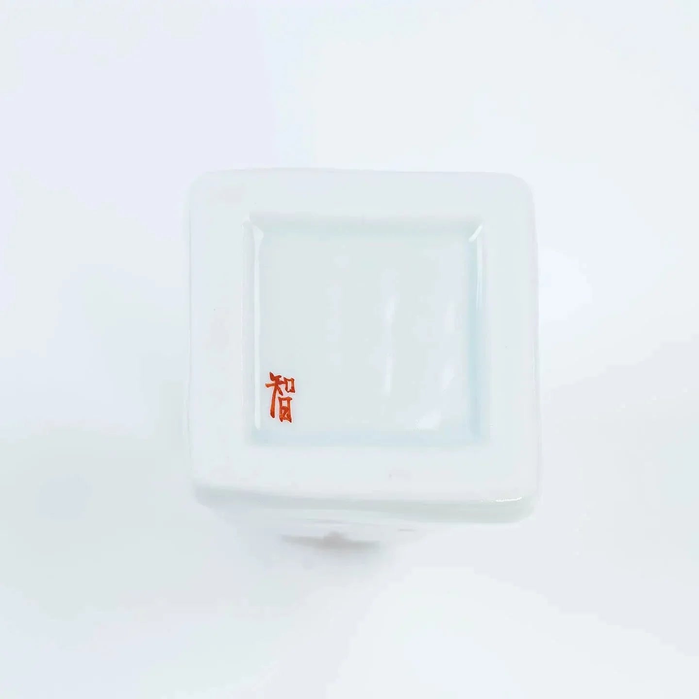 A white Kutani-yaki ceramic vase in the shape of Mt. Fuji with a pink cherry blossom pattern.