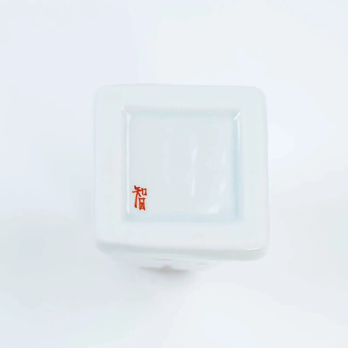 A white Kutani-yaki ceramic vase in the shape of Mt. Fuji with a pink cherry blossom pattern.