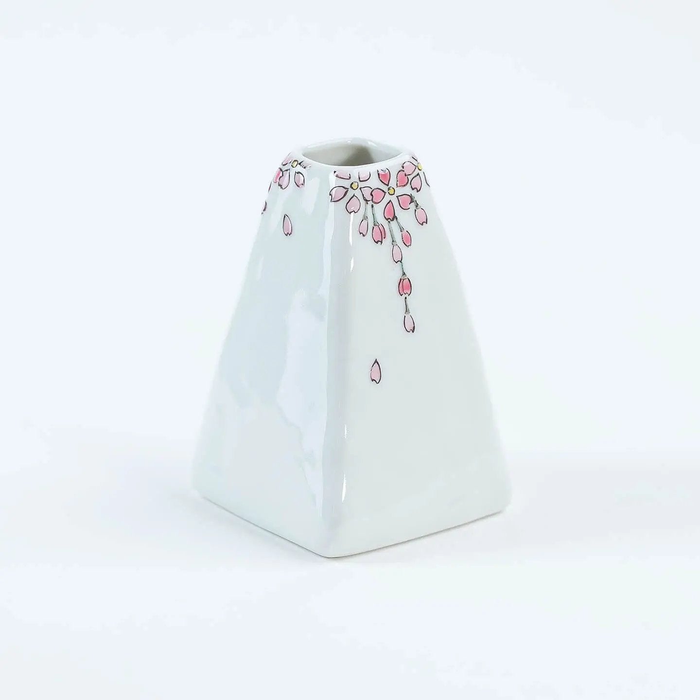 A white Kutani-yaki ceramic vase in the shape of Mt. Fuji with a pink cherry blossom pattern.