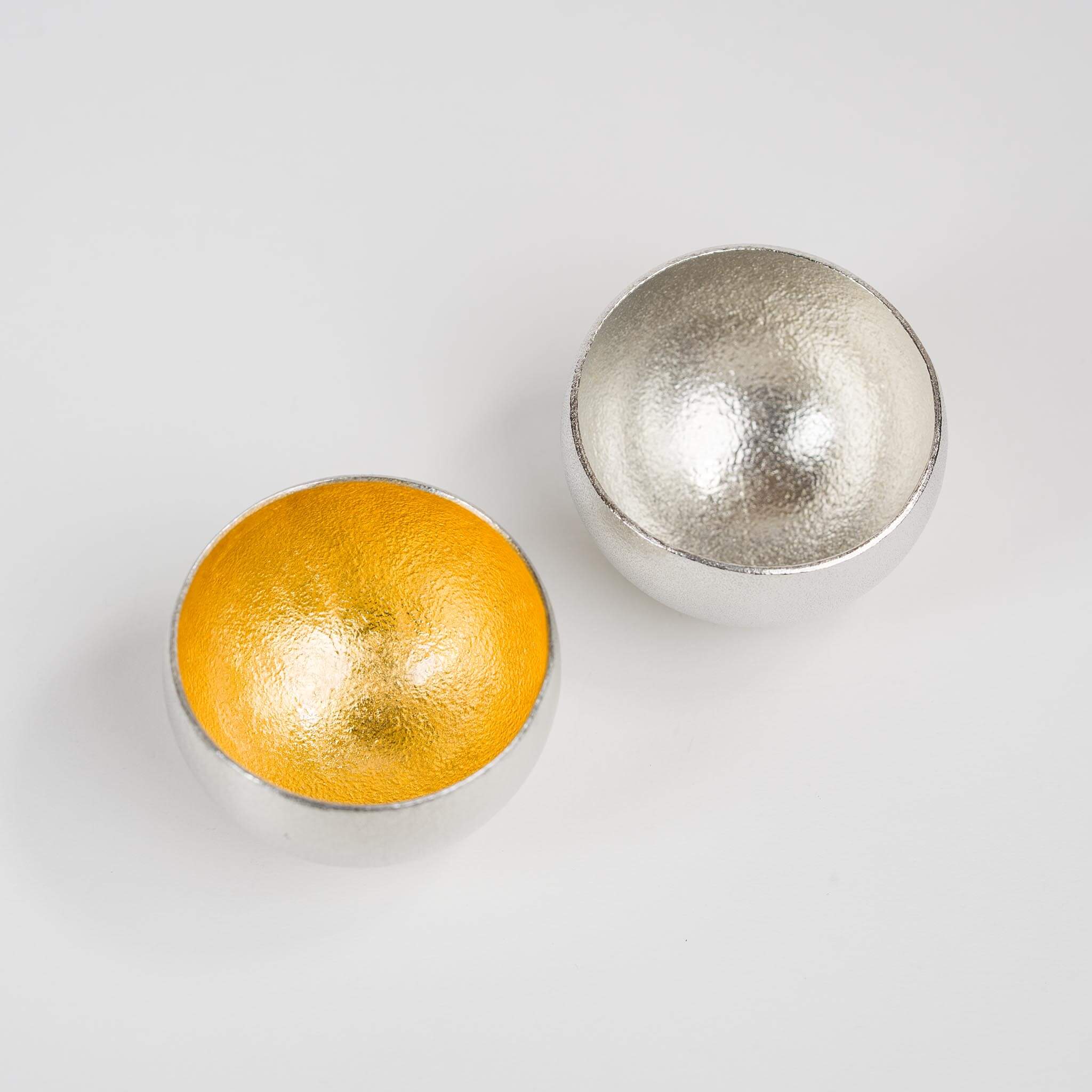 Close-up shot of the rounded base design and the contrasting interior textures of the tin and gold cups.