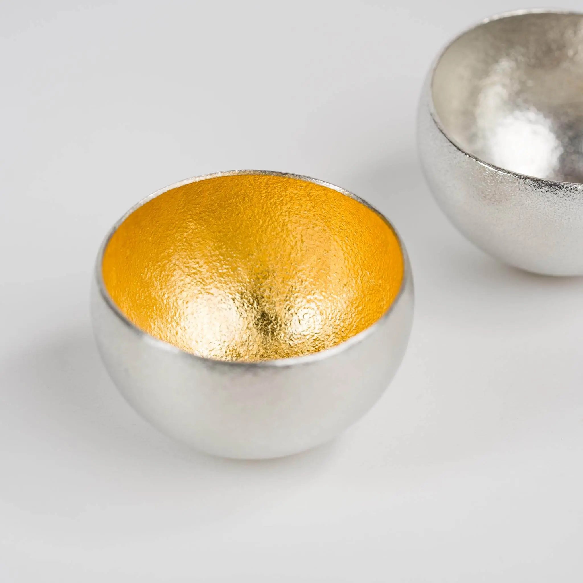 Detailed view of the luxurious gold leaf rim on the swaying tin sake cup.