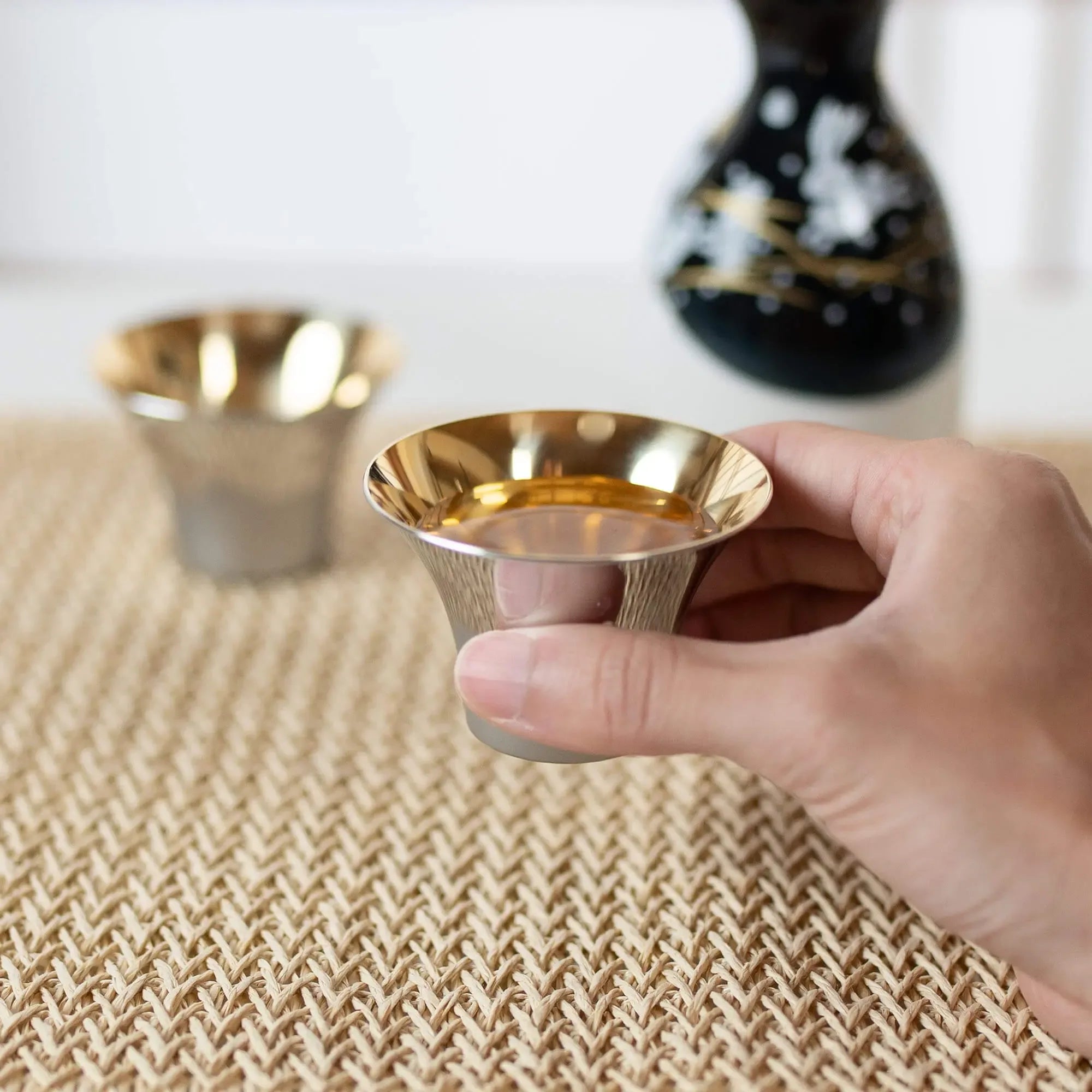 Hand holding Japanese Fuji-shaped stainless steel sake cup
