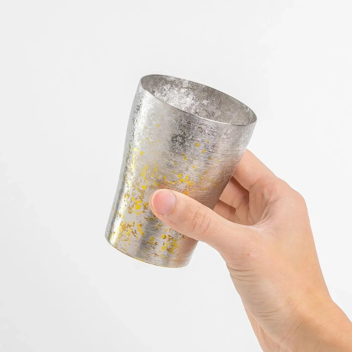 Hand holding the silver and yellow titanium tumbler at an angle.