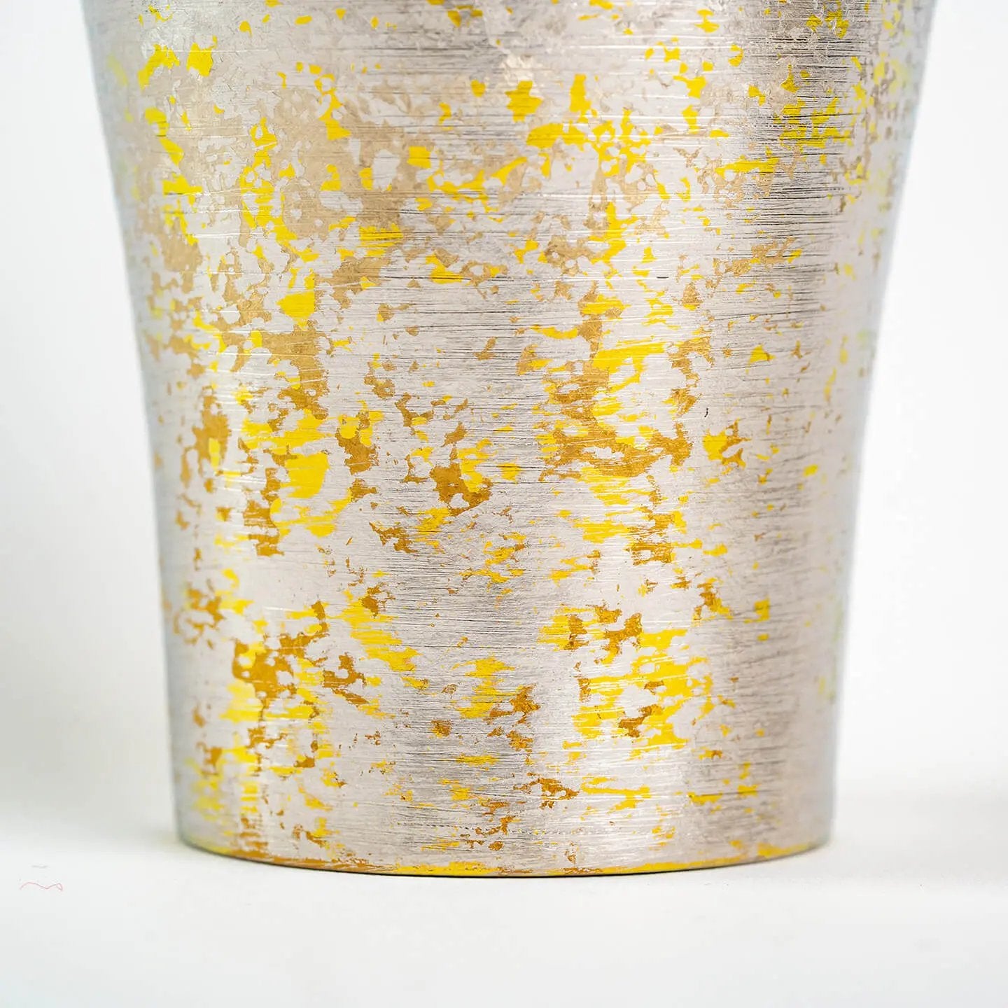 Close-up detail of the tumbler's brushed silver surface with scattered yellow/gold color texture.