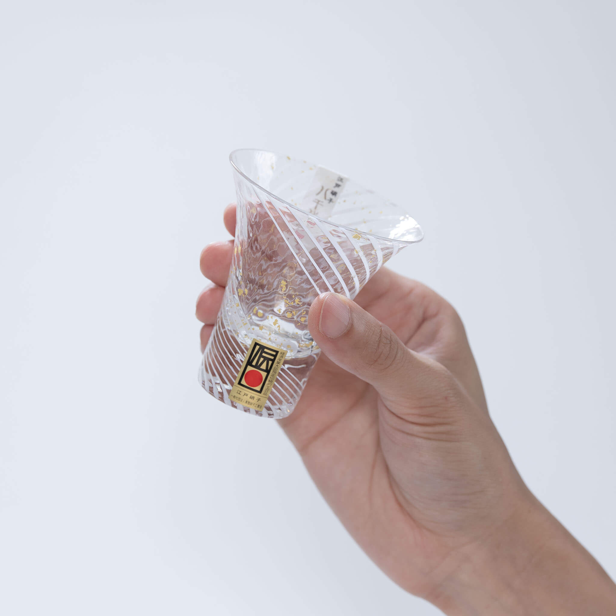 Side view of a hand holding the spiral-patterned Yukimizake sake glass
