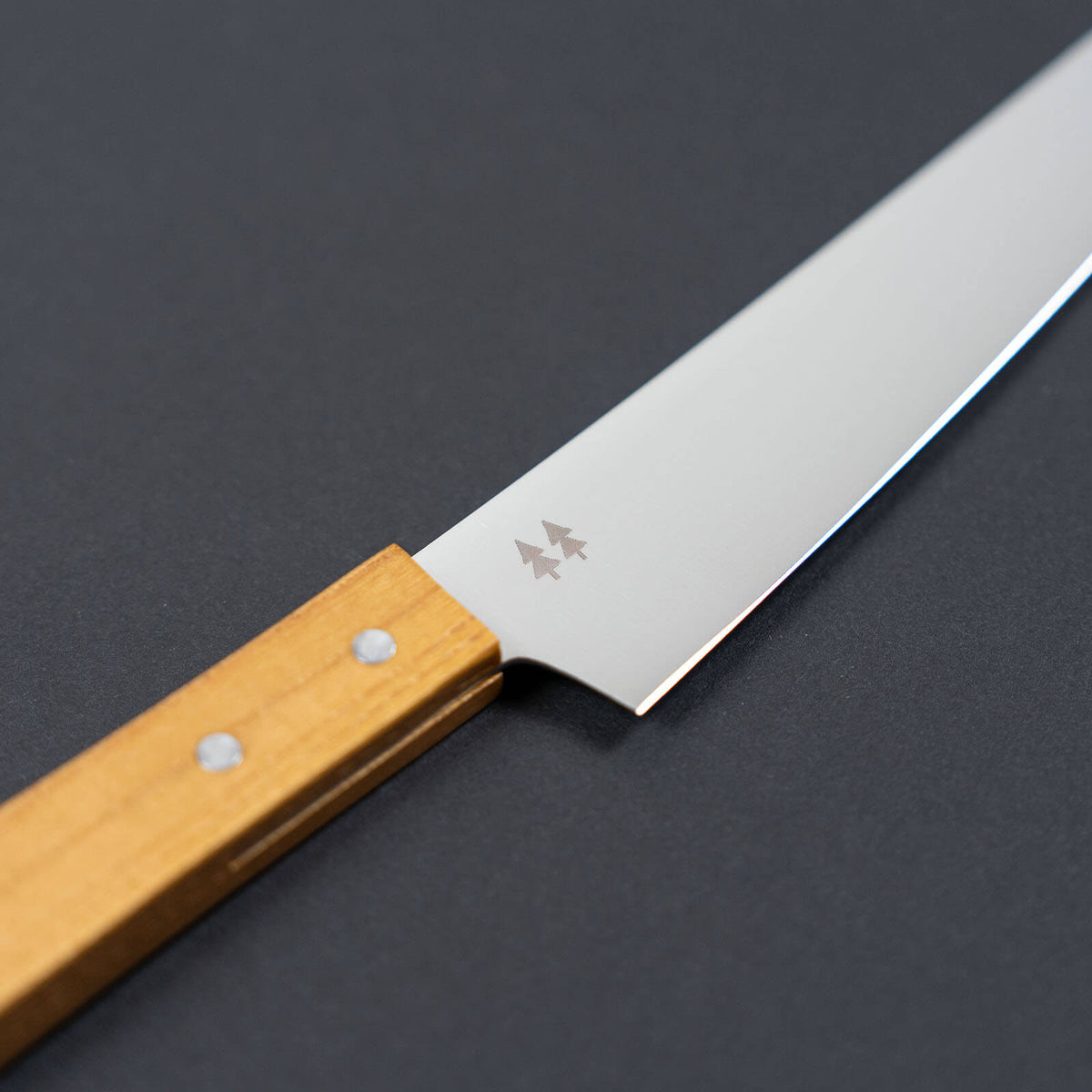 Close-up of the Morinoki tree logo on the stainless steel blade of a Shizuhamono utility knife