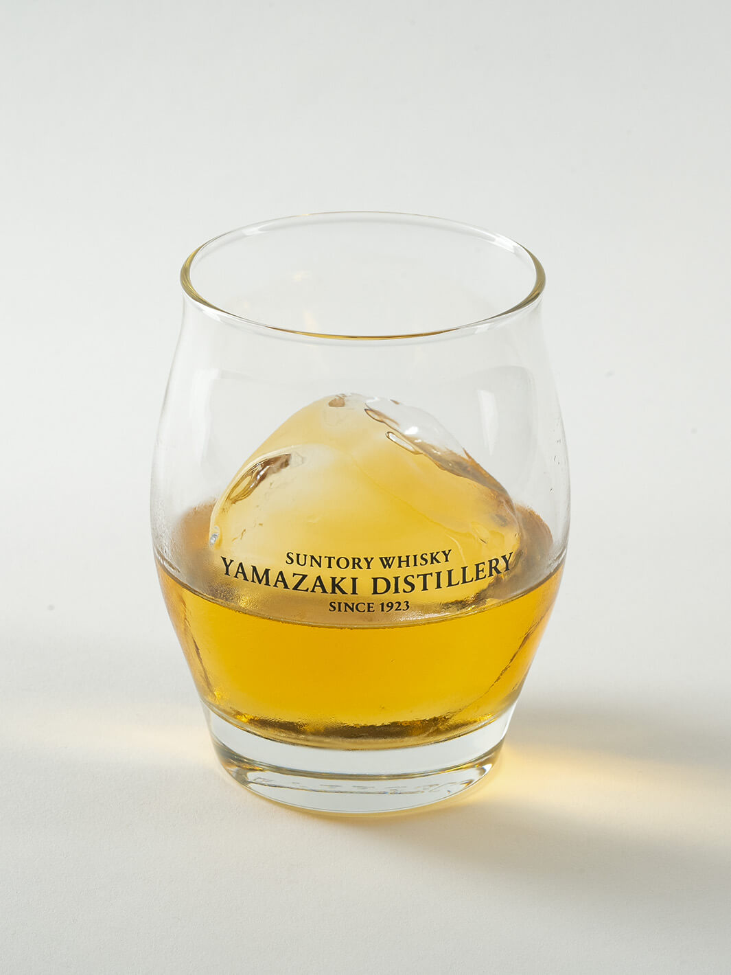 Angled view of Yamazaki ice ball whiskey glass with whisky and ice