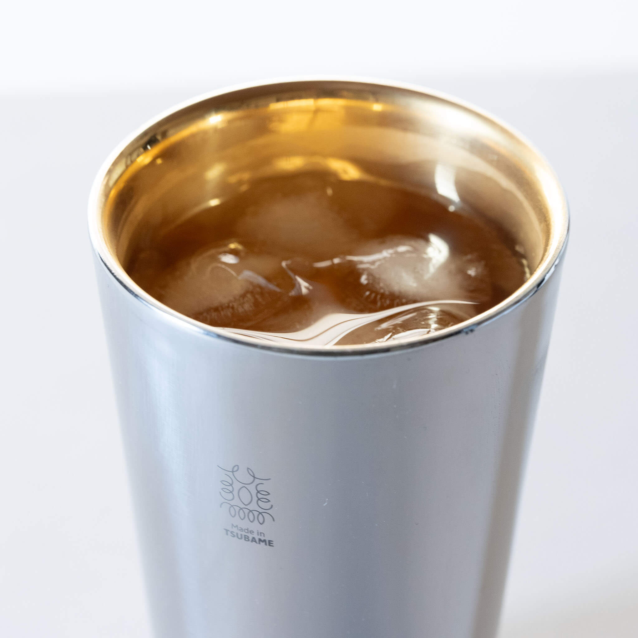Close-up of the luxurious 24K gold-plated interior of a Japanese double-wall insulation cup with ice.