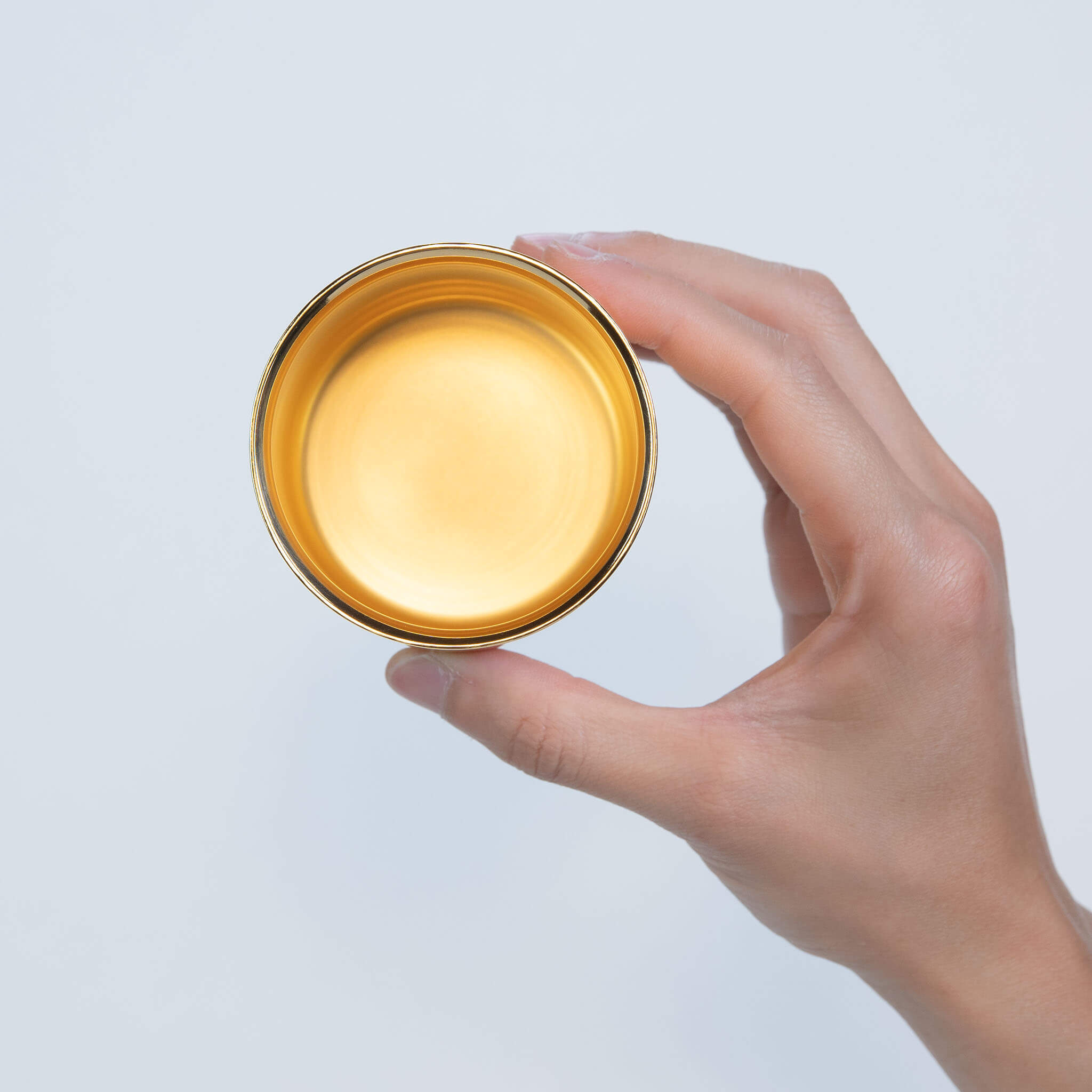 Top view of a person holding the stainless steel tumbler, highlighting the brilliant 24K gold plated interior for beverages.