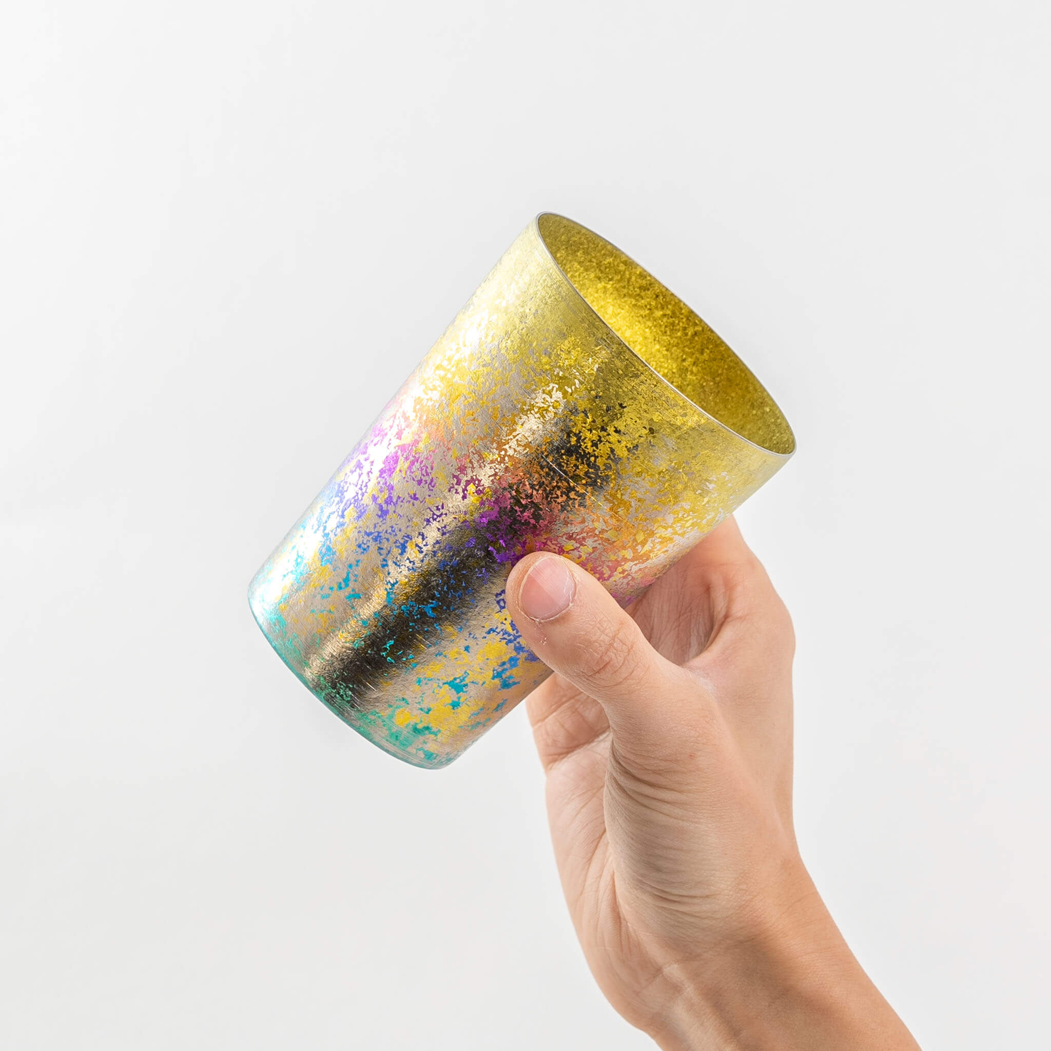 Side view of a hand holding the rainbow HORIE Taiko titanium tumbler