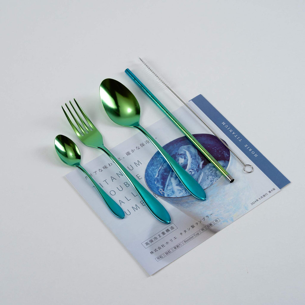 Green gradient HORIE pure titanium cutlery set arranged on a Japanese magazine