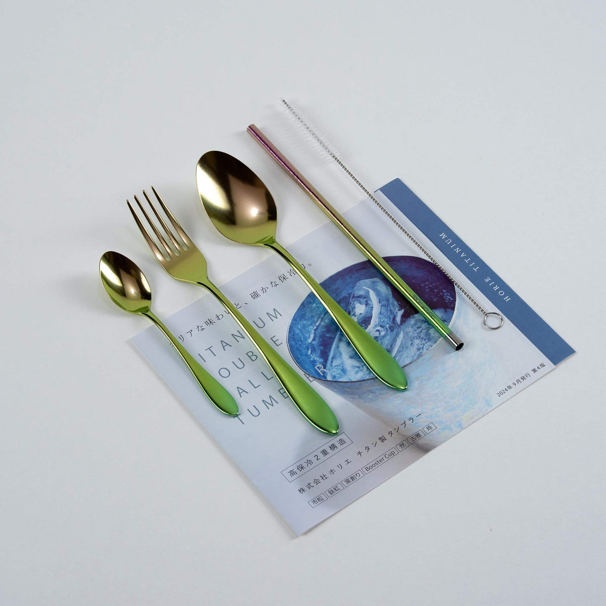 Pink gradient HORIE pure titanium cutlery set arranged on a Japanese magazine