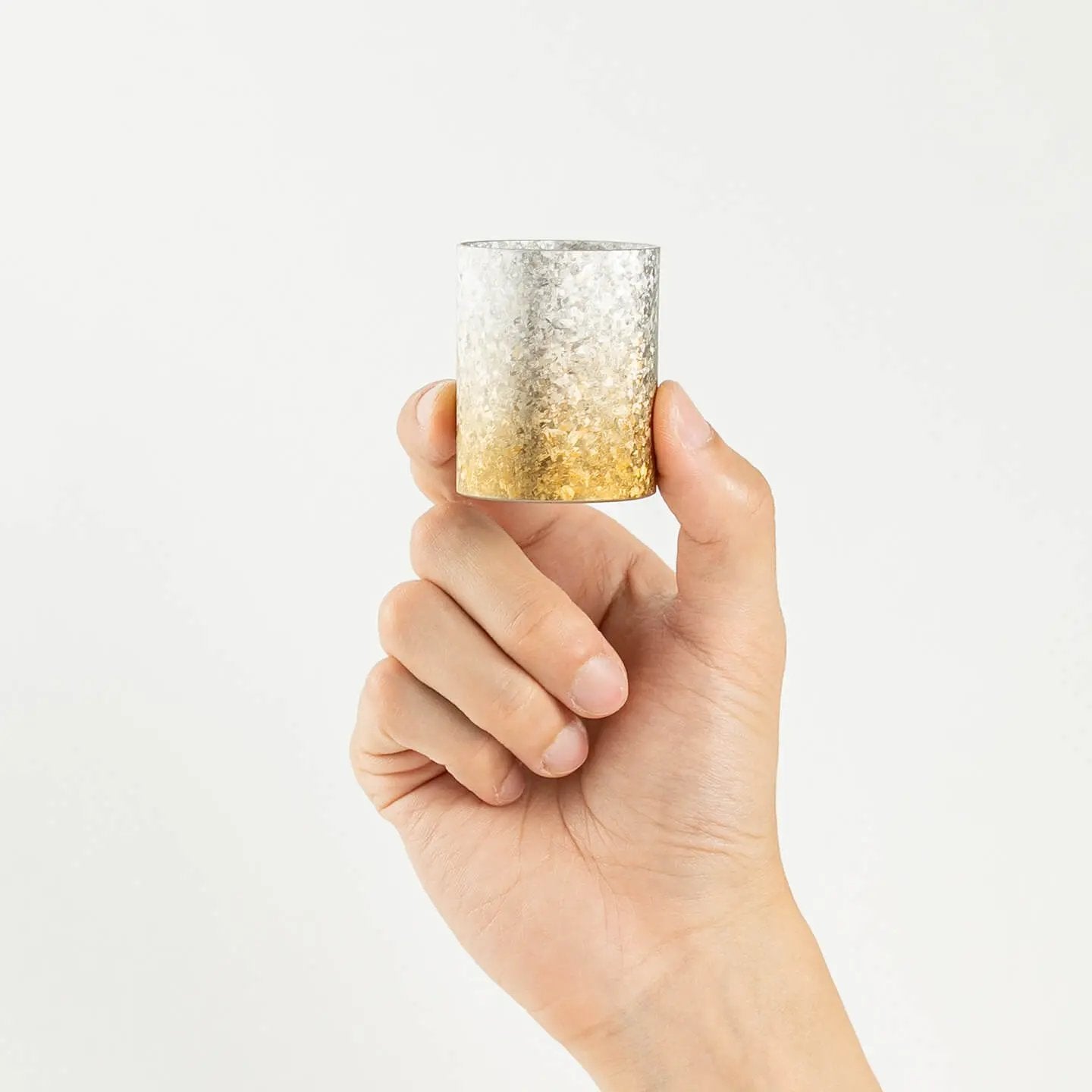 A hand holding the HORIE Titanium Sake Cup to demonstrate its size and scale.