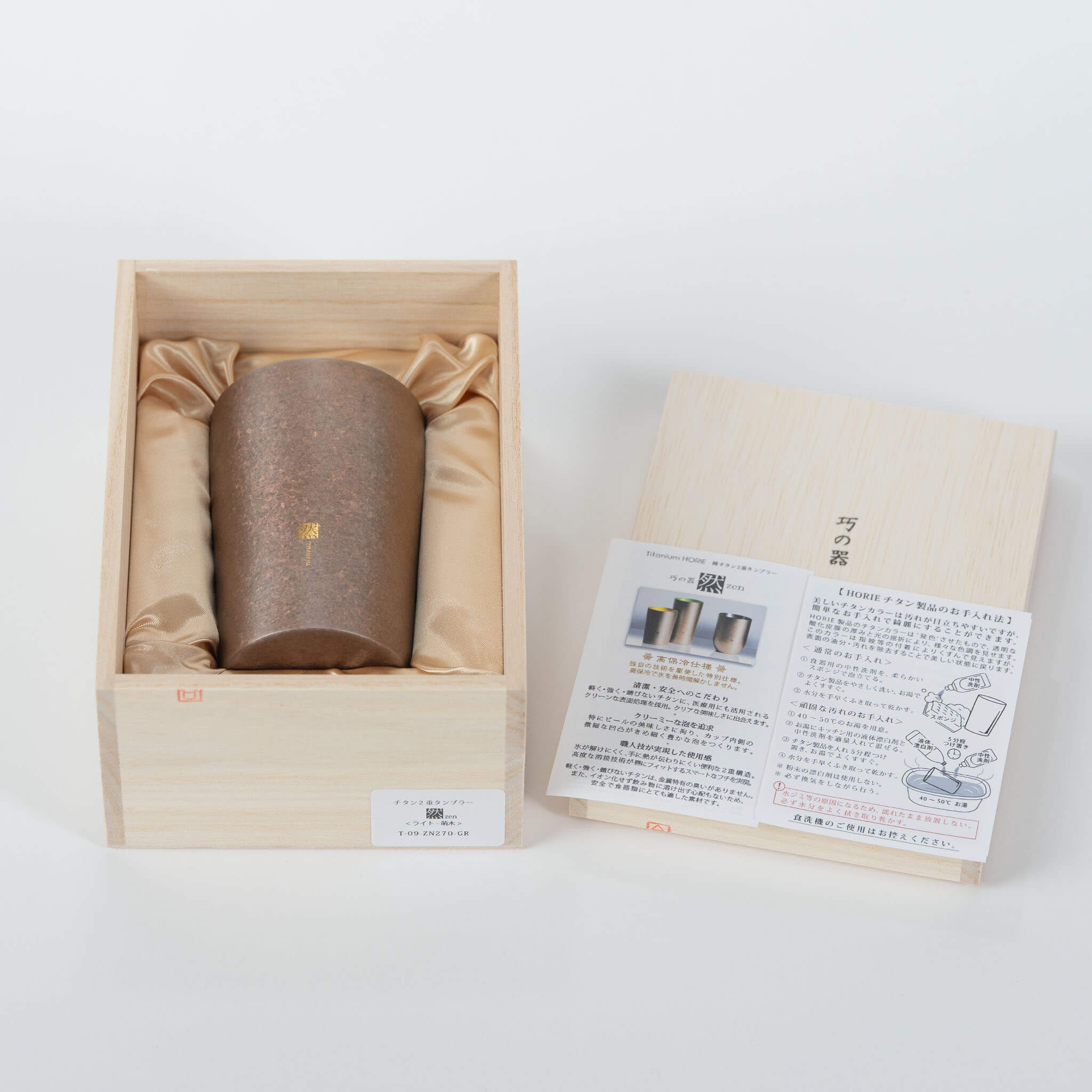 A top-down view of the Horie Zen 270ml titanium tumbler standing in its traditional wooden gift box alongside the lid.