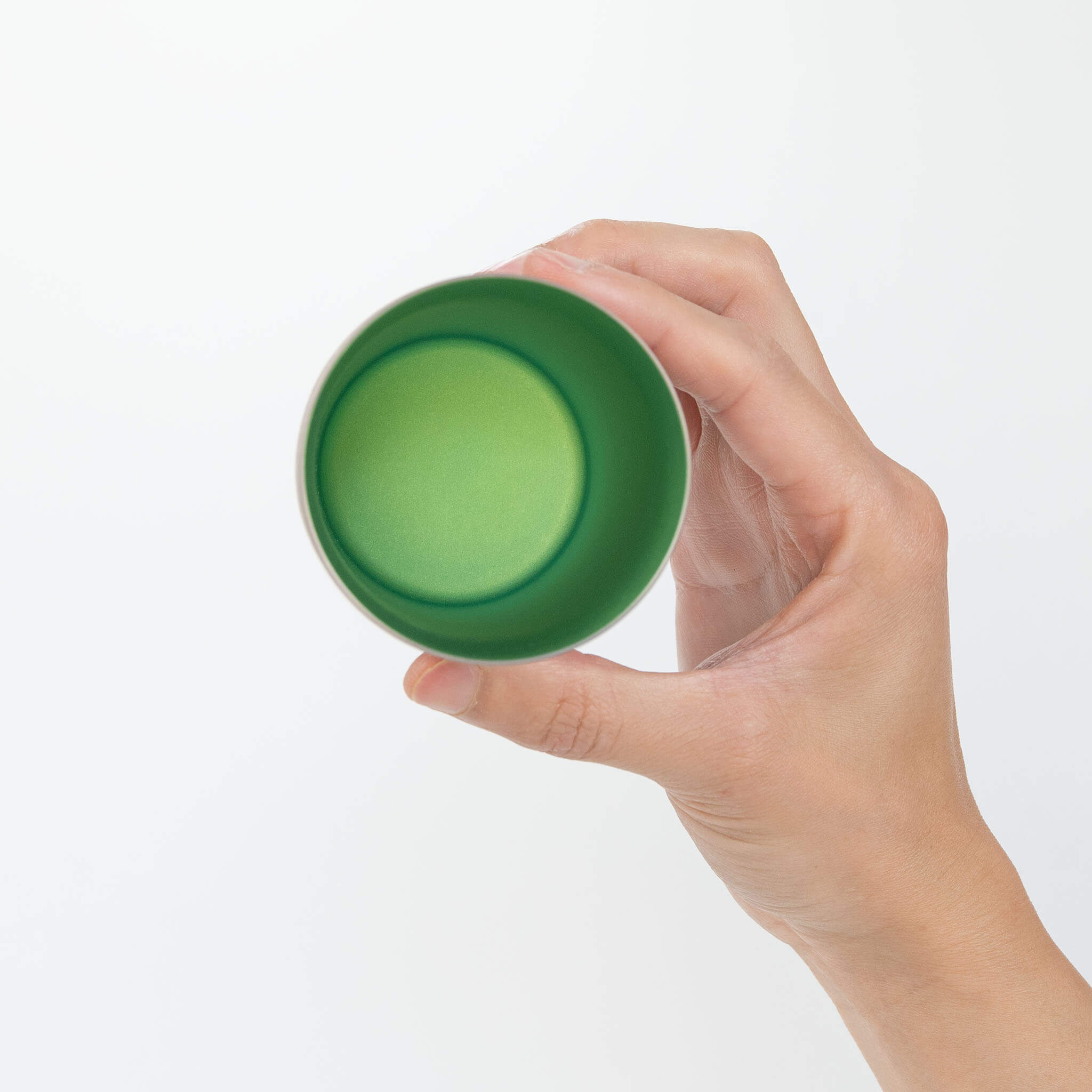 A top-down view of a person holding the Horie Zen 270ml titanium tumbler, beautifully showcasing the vibrant green anodized interior color.