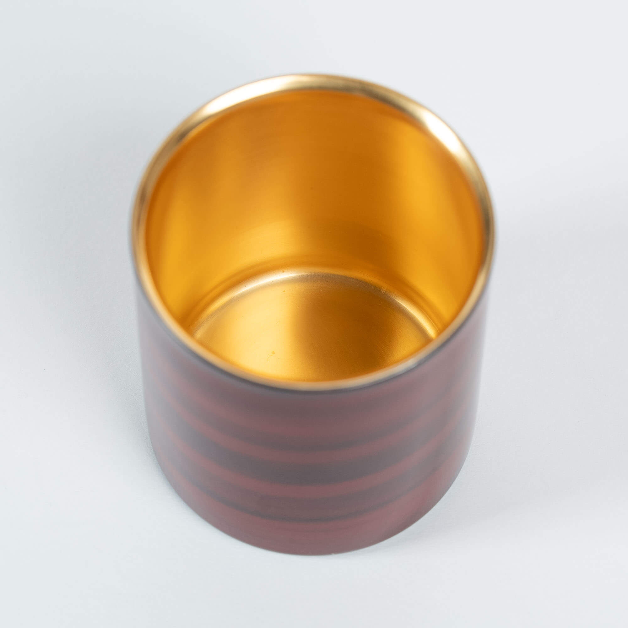 Angled top view of a red lacquered sake cup with a reflective gold-plated interior