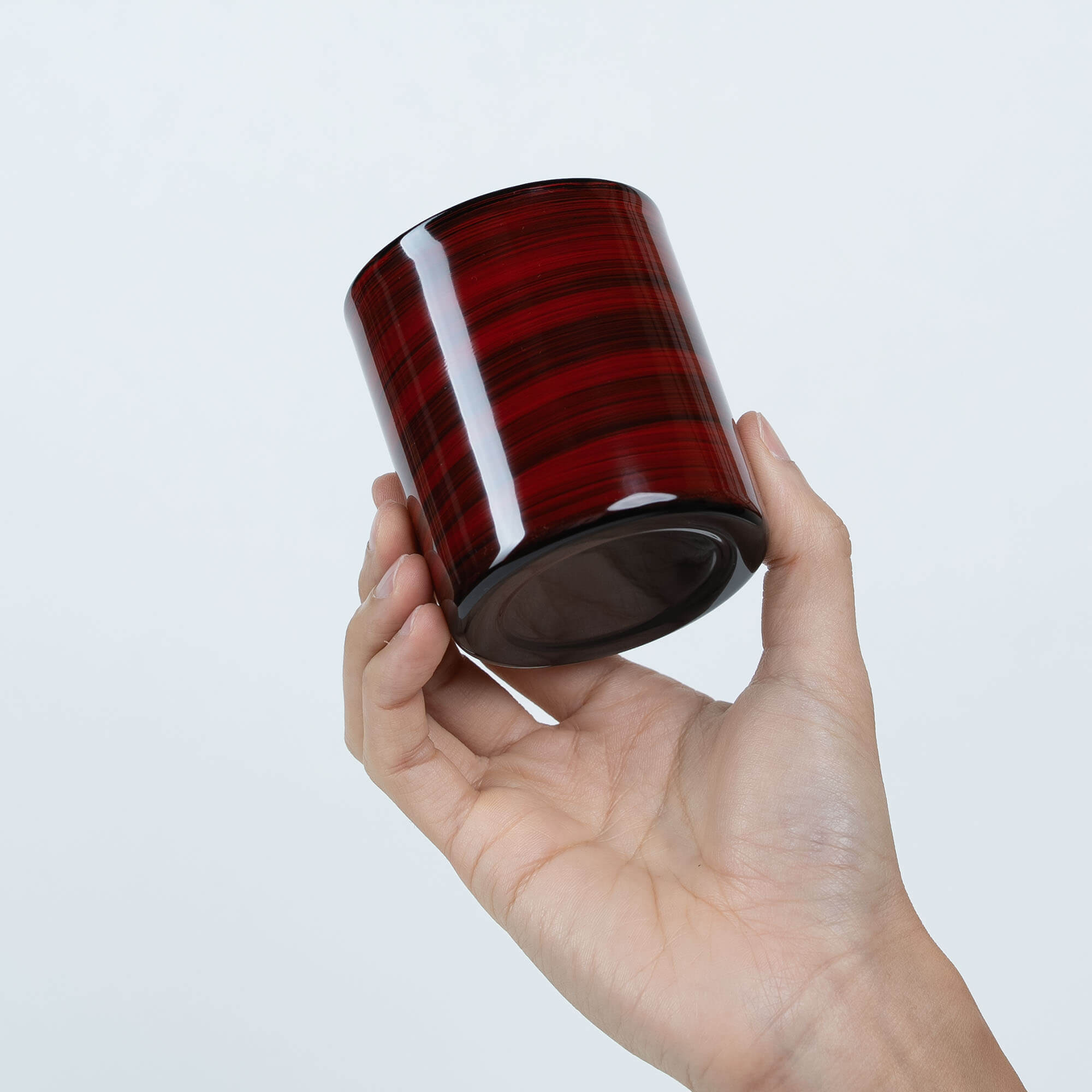 Angled base view of a red Japanese lacquered sake cup held in one hand